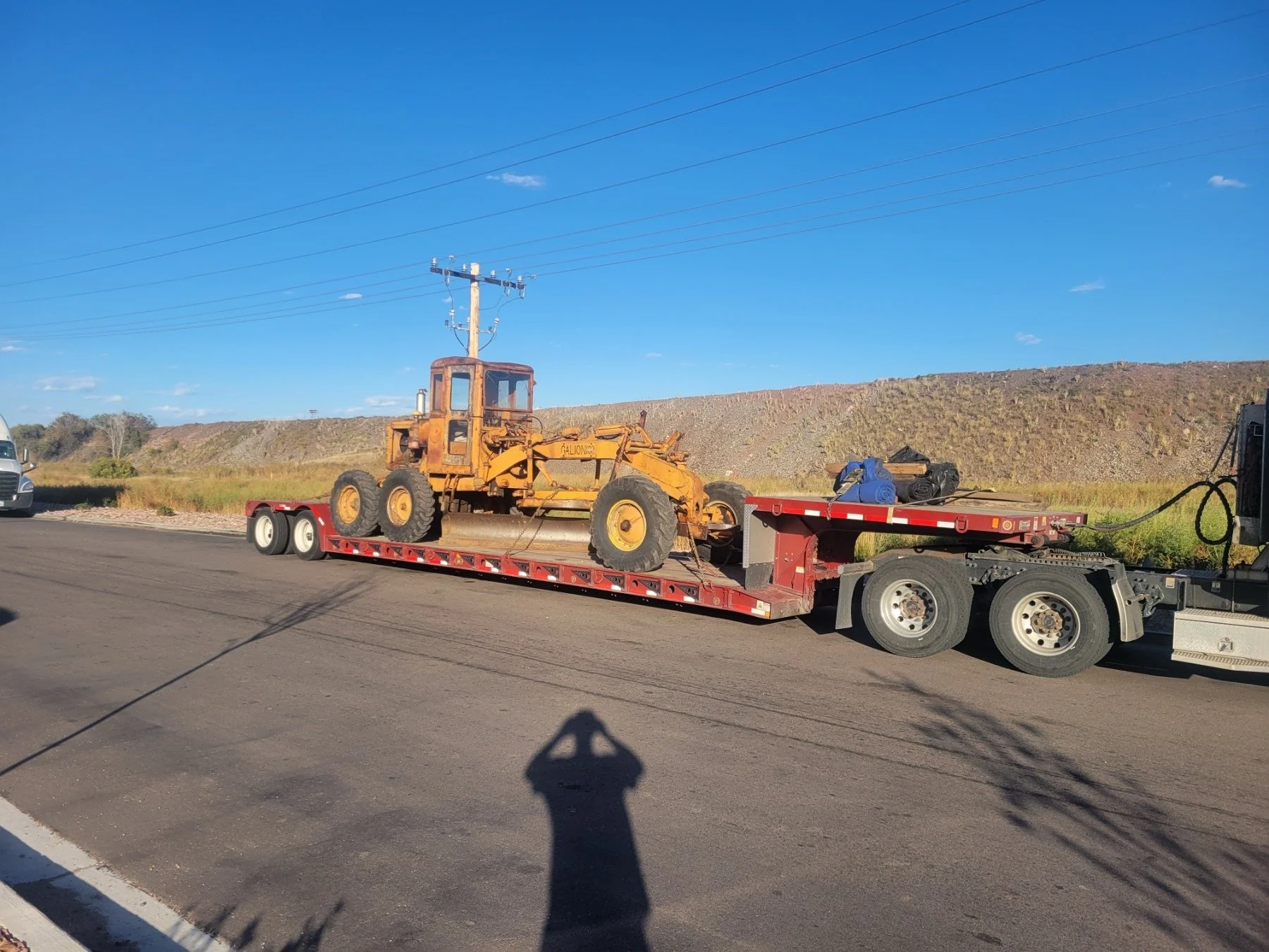 Motor grader Galion transported on RGN trailer through mountain highway – Prime Load Solutions
