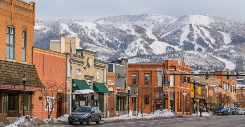 Buena Vista Main street in a snowy town with brick buildings and a mountainous backdrop.