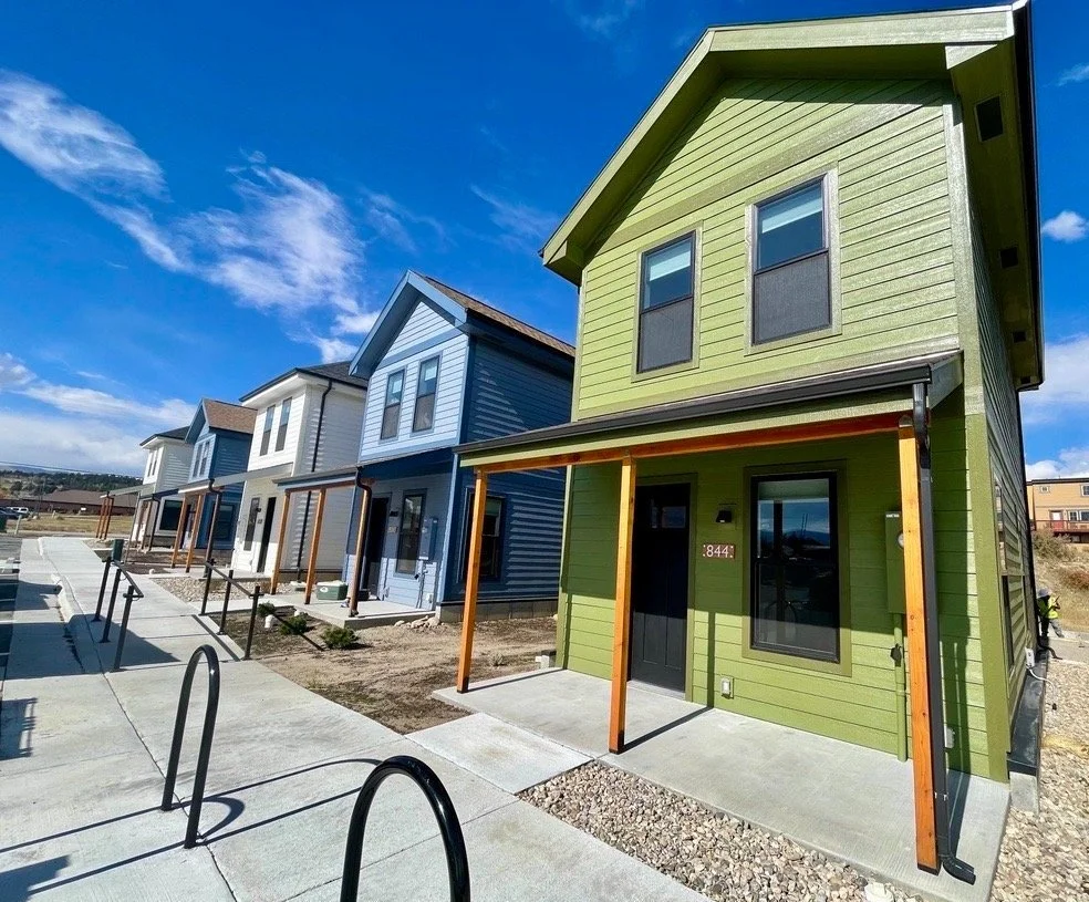 Fading West CDOT workforce housing project in Fairplay, Colorado — colorful modern single family modular homes with front porches on a sunny day.