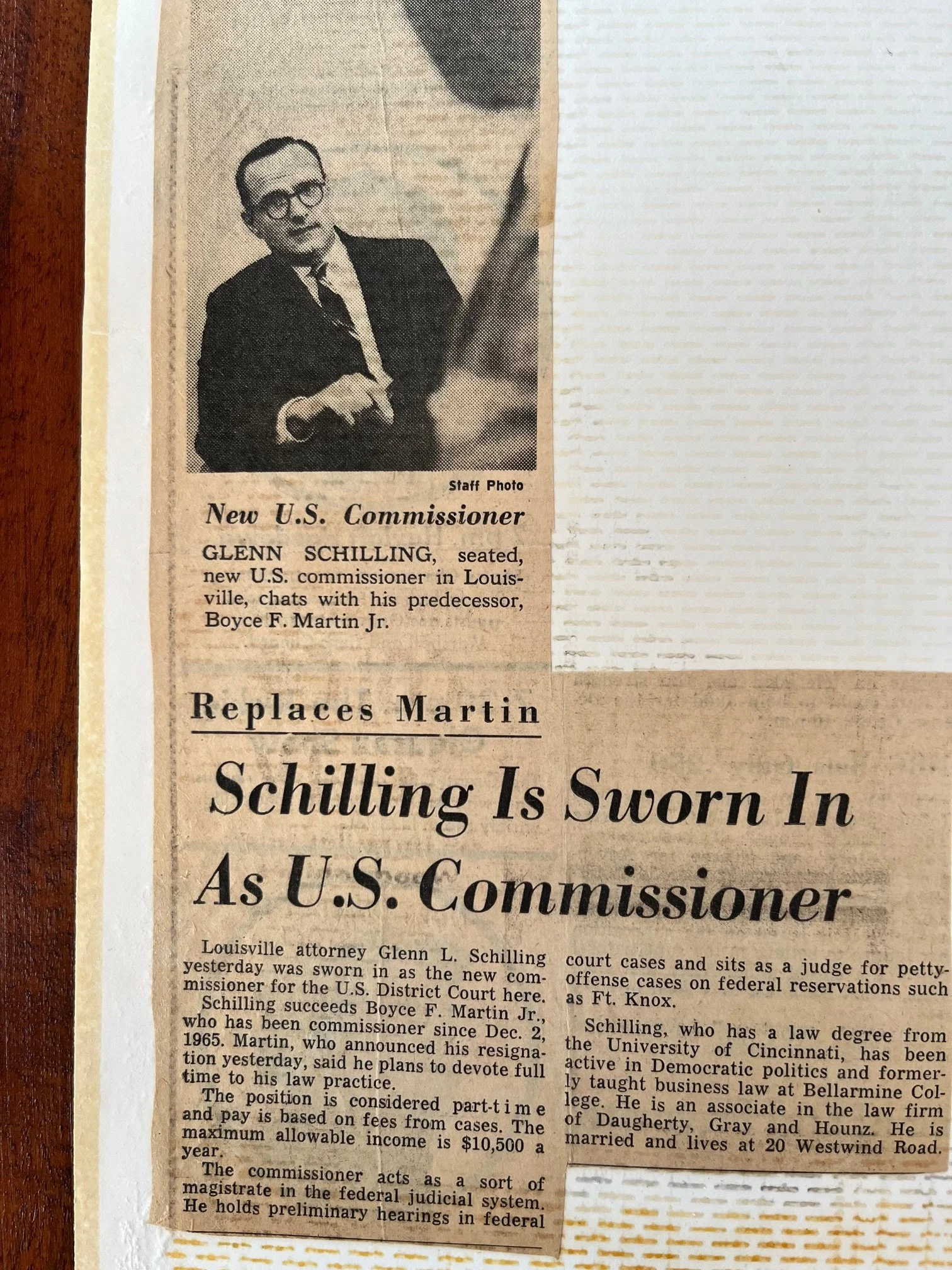 Black and white newspaper clipping featuring a photograph of Glenn Schilling, a man with glasses, dressed in a suit, sitting at a desk. The headline reads, "Replaces Martin Schilling Is Sworn In as U.S. Commissioner." The text mentions Glenn Schilling being sworn in as a U.S. commissioner in Louisville, replacing Boyce F. Martin Jr. and discusses his background and qualifications.