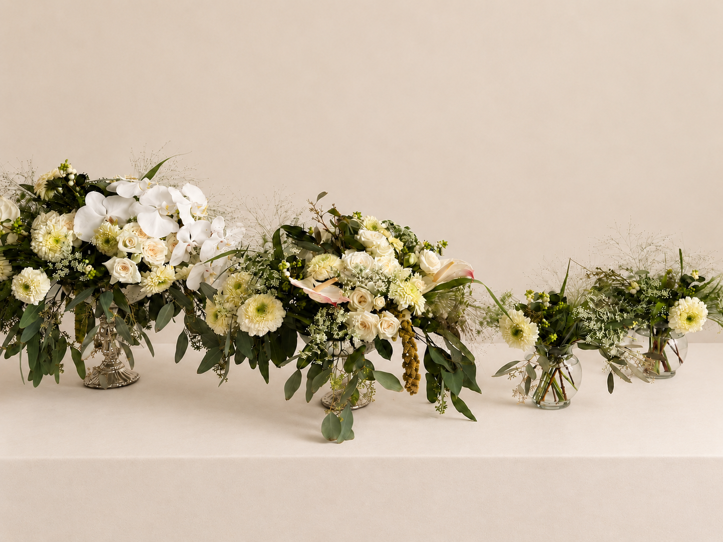 White and green floral arrangements by Grove Floral Studios in Miami, featuring orchids, roses, gerberas, airy textures, and seasonal greenery styled across multiple vessels for an elegant event tablescape.