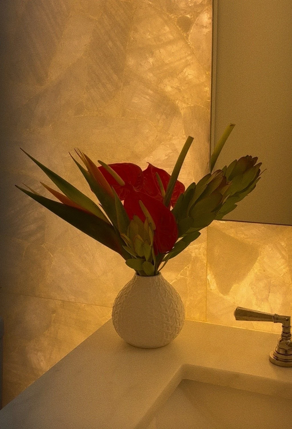 Small restroom arrangement with anthurium, birds of paradise & leucadendron in a white vase.