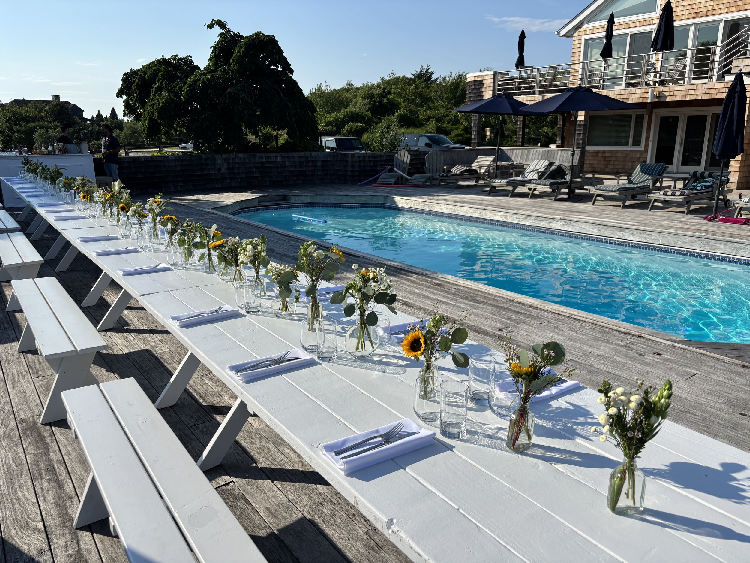 Designed for a private gathering in Montauk, this tablescape embraced the beauty of restraint. Individual bud vases filled with seasonal flowers brought texture, movement, and color to a long communal table overlooking the water. By Grove Floral Stud