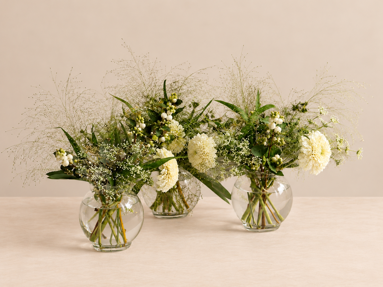 White and green floral arrangement by Grove Floral Studios in Miami, featuring orchids, roses, gerberas, airy textures, and seasonal greenery in an elegant silver pedestal vase.