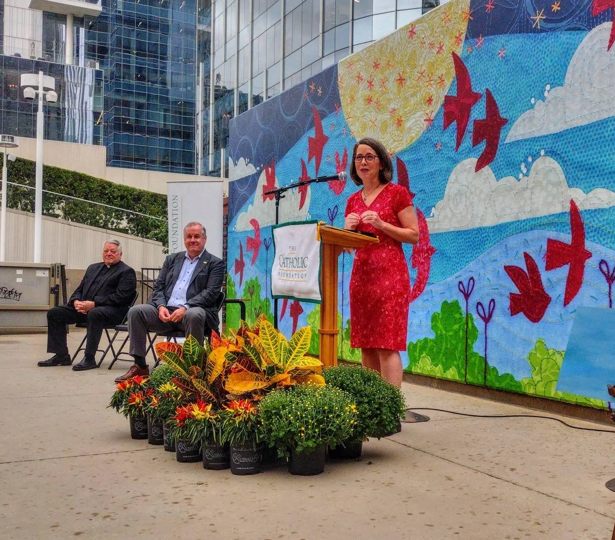 Speaker at a podium during the public unveiling ceremony for Deborah Boschert's Looking Up mural.