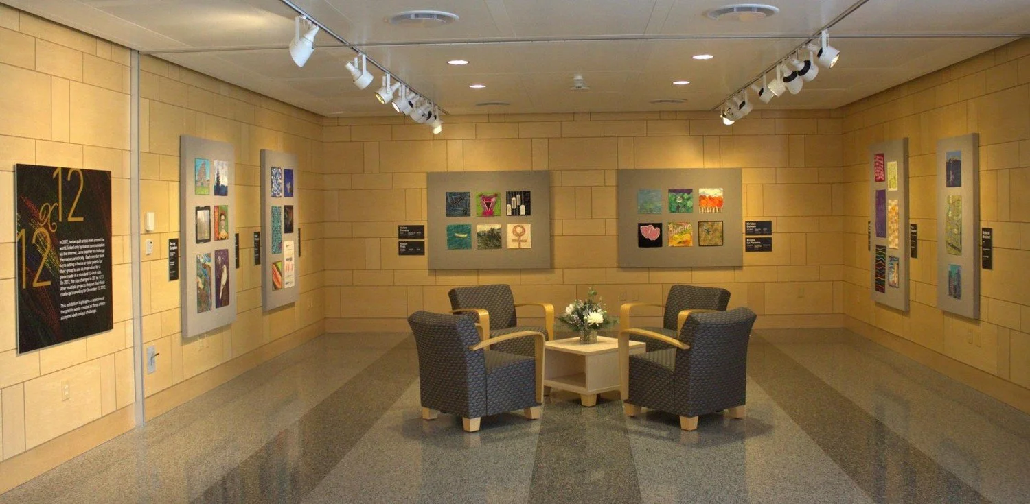 Wide panoramic view of the Twelve by Twelve art quilt gallery installation with quilts on every wall.