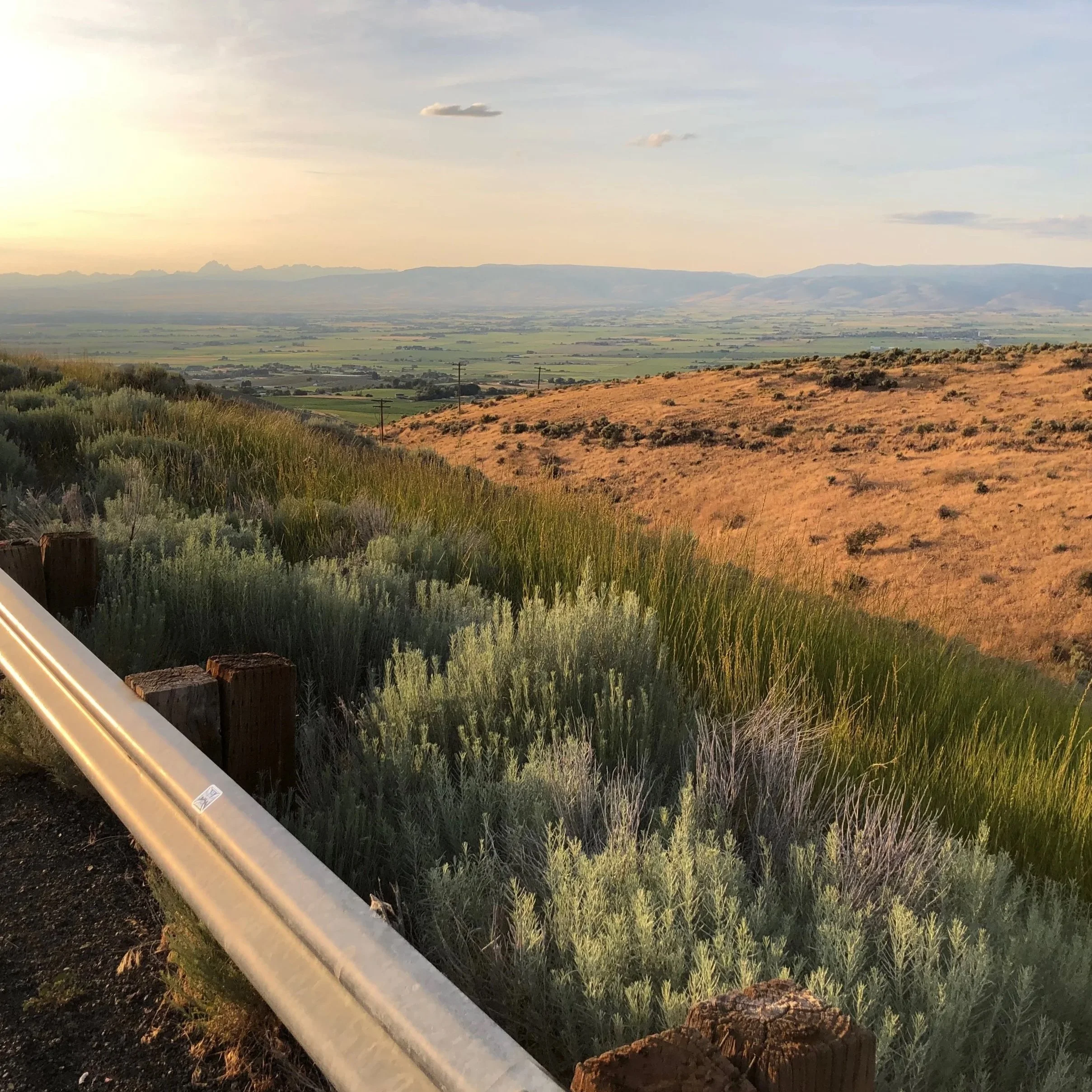 View of a hazy valley, over two rolling hills that meet in the middle.