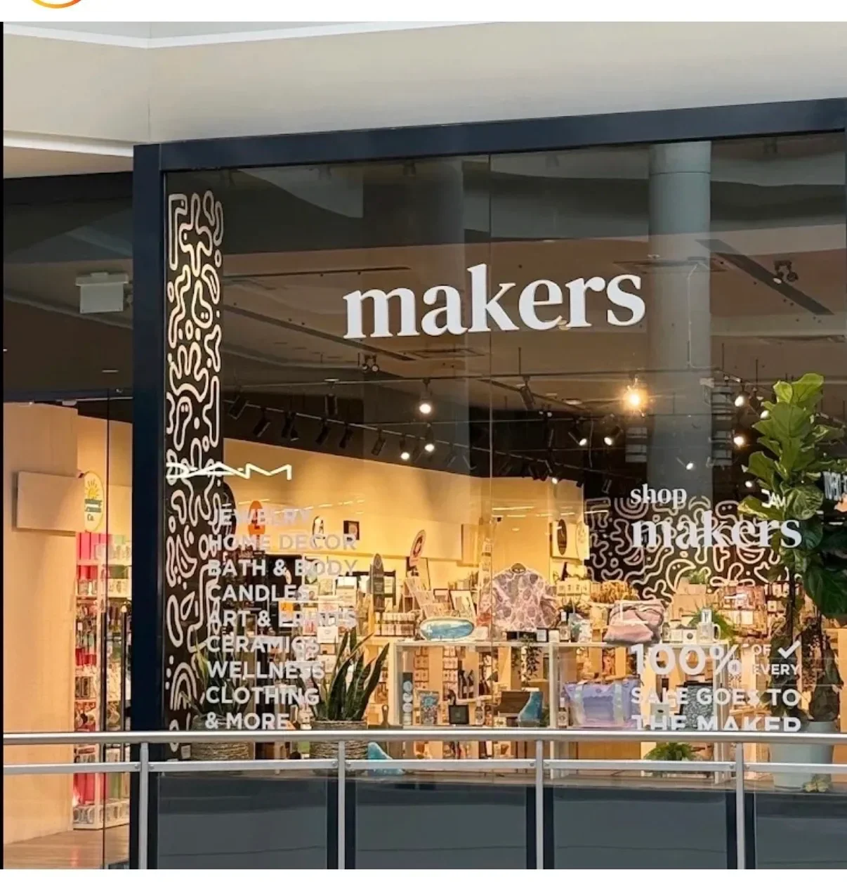 Storefront window display for myers, showcasing home decor, bath and body products, candles, art, ceramics, wellness items, clothing, and more inside a shopping mall.