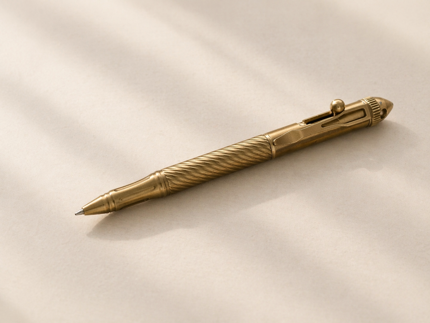 A gold-colored ballpoint pen with a twisted design on the barrel, resting on a plain light-colored surface.