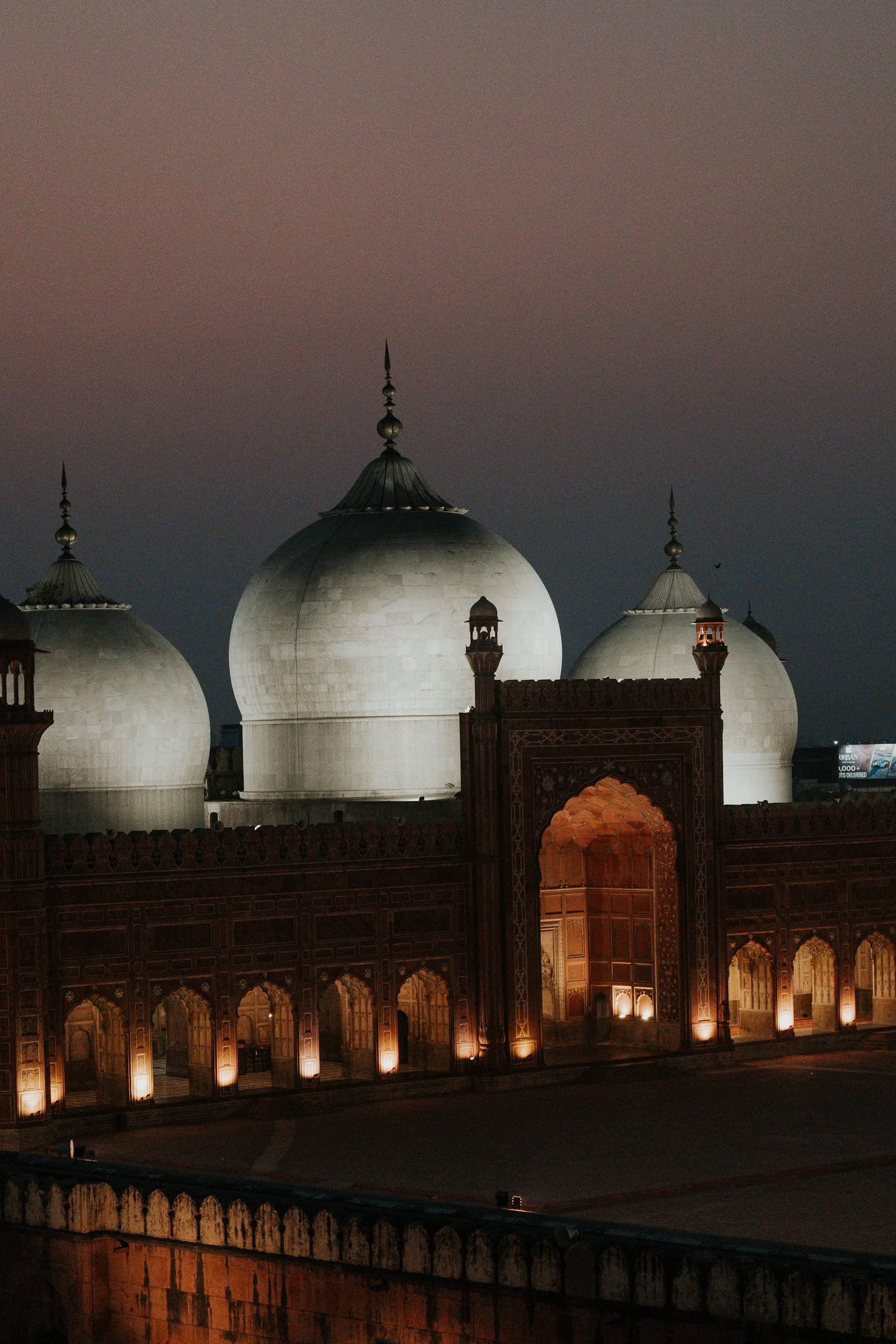 Nighttime view of the Taj Mahal with illuminated arches and domes under a dark sky.