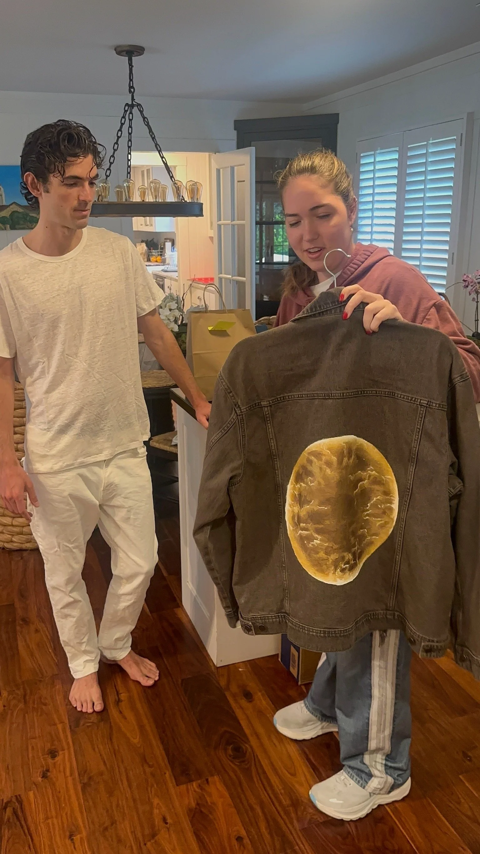 Elle and a customer talking while holding a black denim jacket with a moon on it