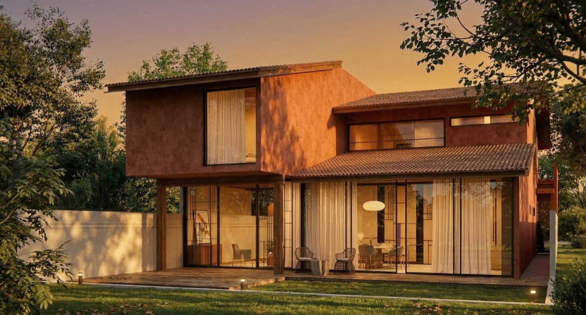 Casa moderna de dos pisos con paredes de color terracota, grandes ventanas de vidrio y un porche con muebles, rodeada de árboles y césped en una tarde soleada.