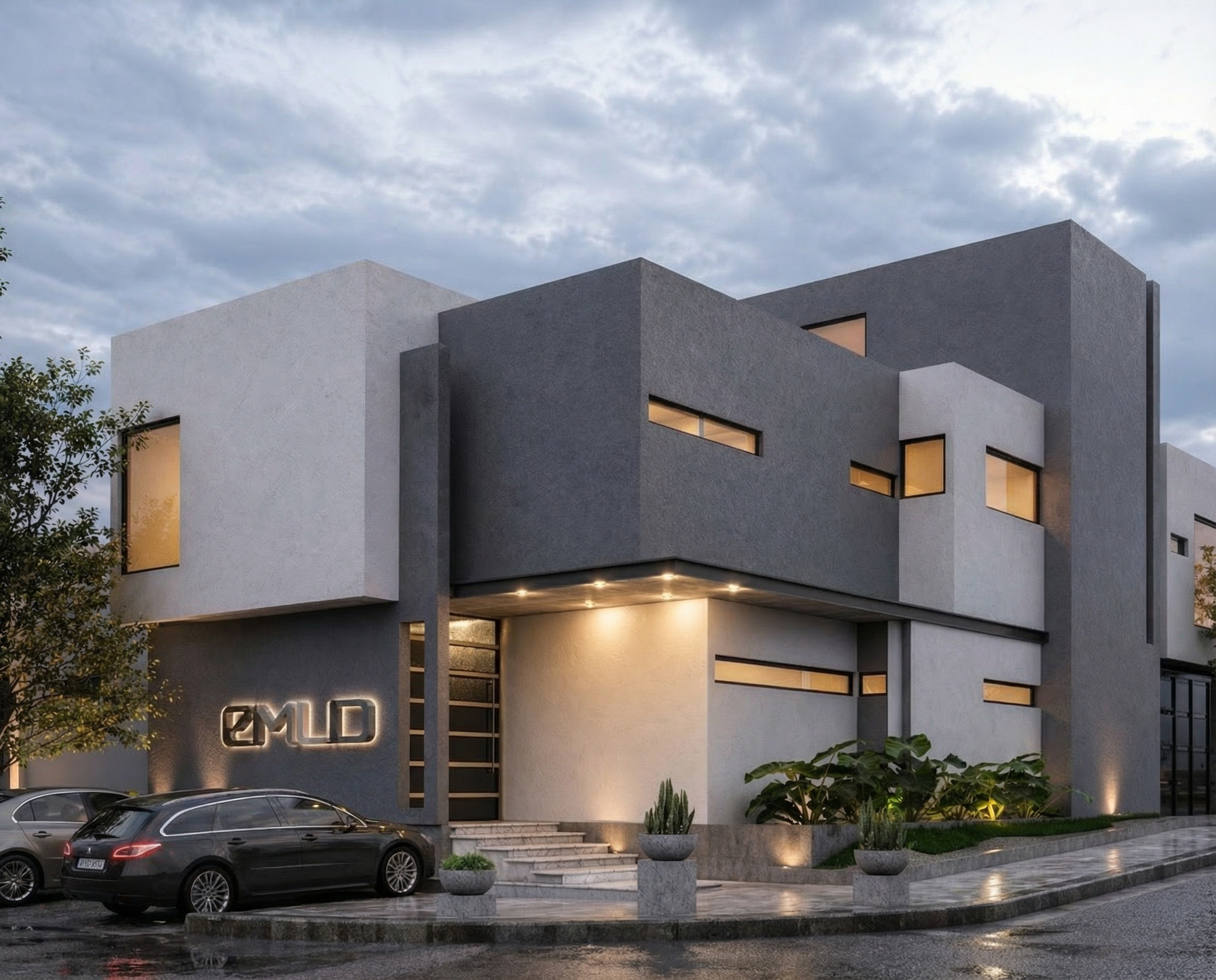 Edificio moderno con ventanas rectangulares y fachada de color gris, algunas con luz encendida, con árboles y plantas en la entrada y autos estacionados en el frente, bajo un cielo nublado