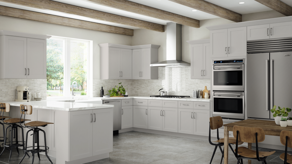 Modern kitchen with white cabinets, stainless steel appliances, a wooden ceiling beam, a window with a view of trees, and a kitchen island with bar stools.