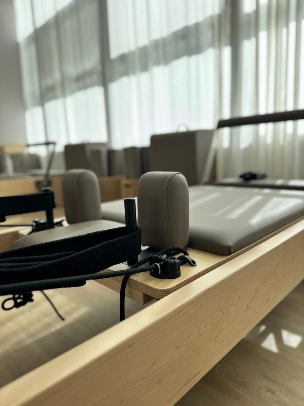 Mesa de madera con equipo de ejercicio, cojines, y ventanas con cortinas en el fondo.