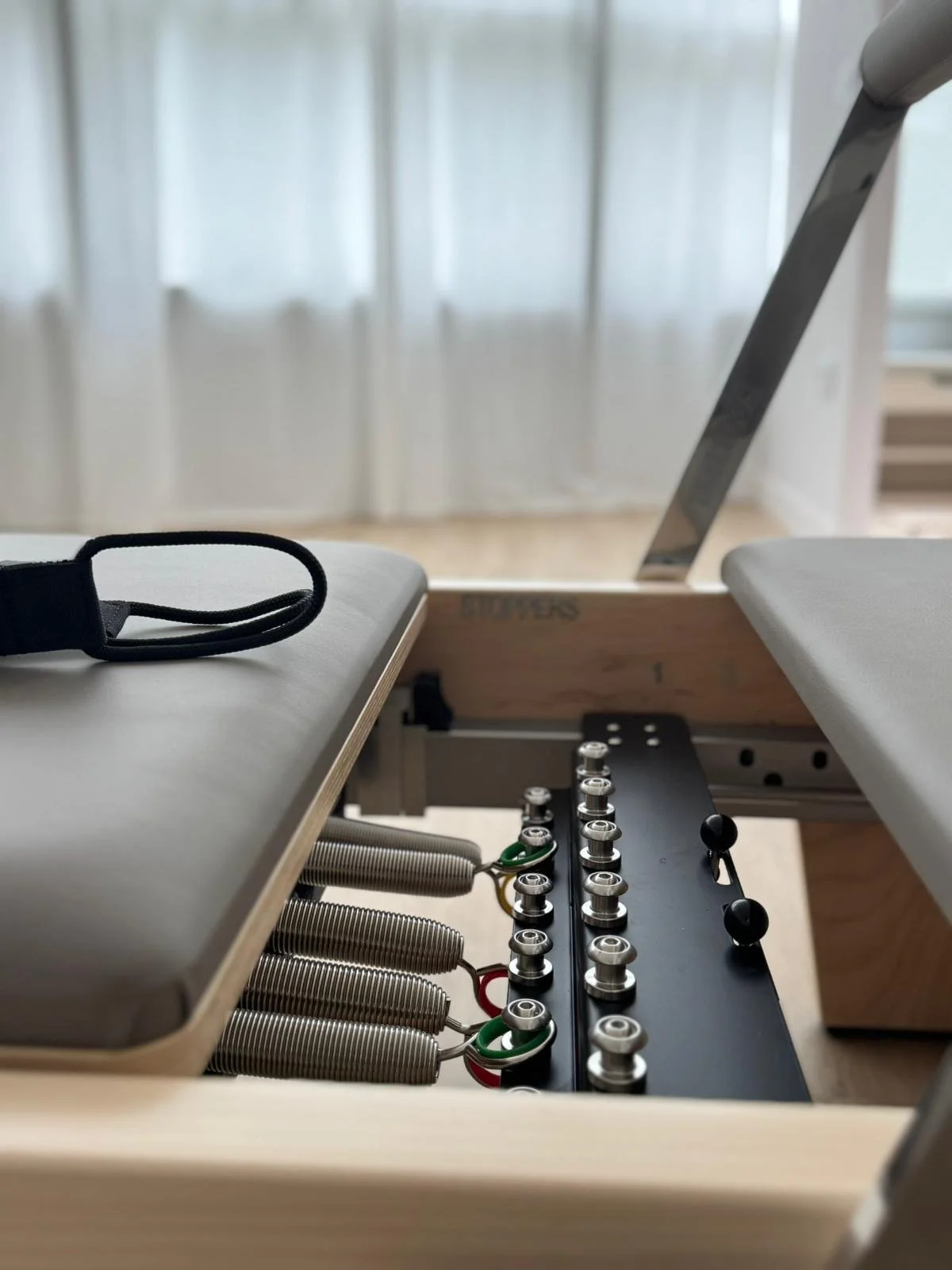 Detalles internos de una maquina de pilates reformer, mostrando los resortes y su mecanismo.