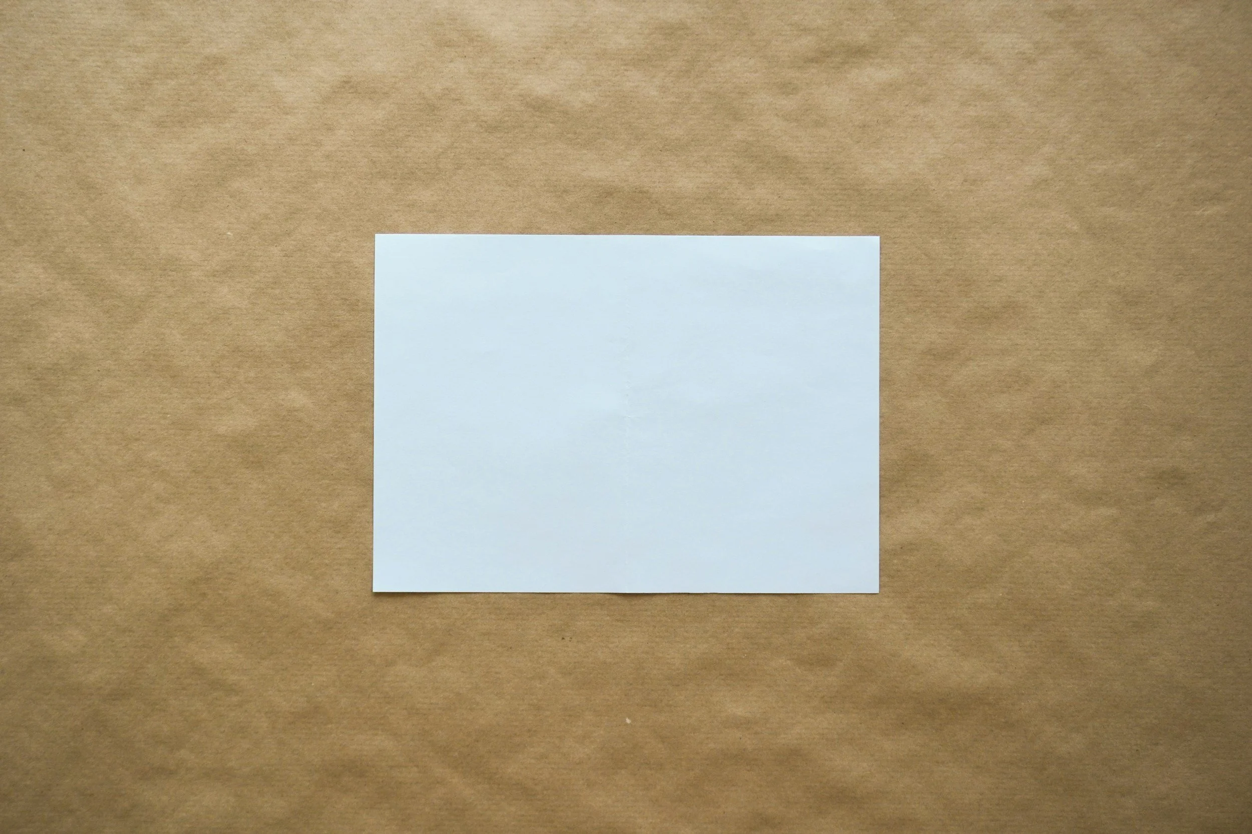 A brown paper bag with a white blank sticky note attached to it.