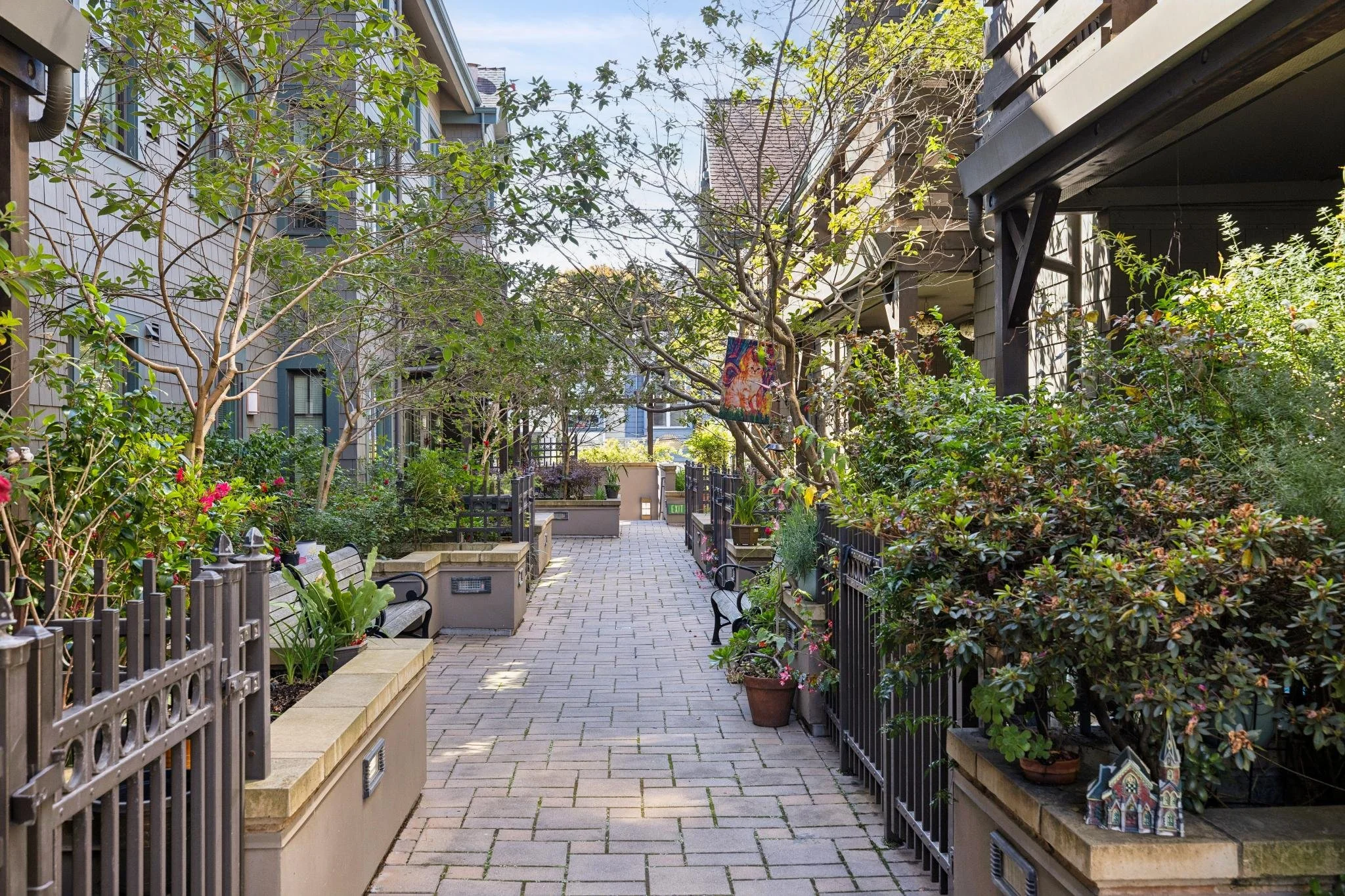 Modern living room with large windows, a brown leather sofa with an orange pillow, a blue armchair, a glass-top dining table with wooden chairs, and abstract blue artwork on the white wall.