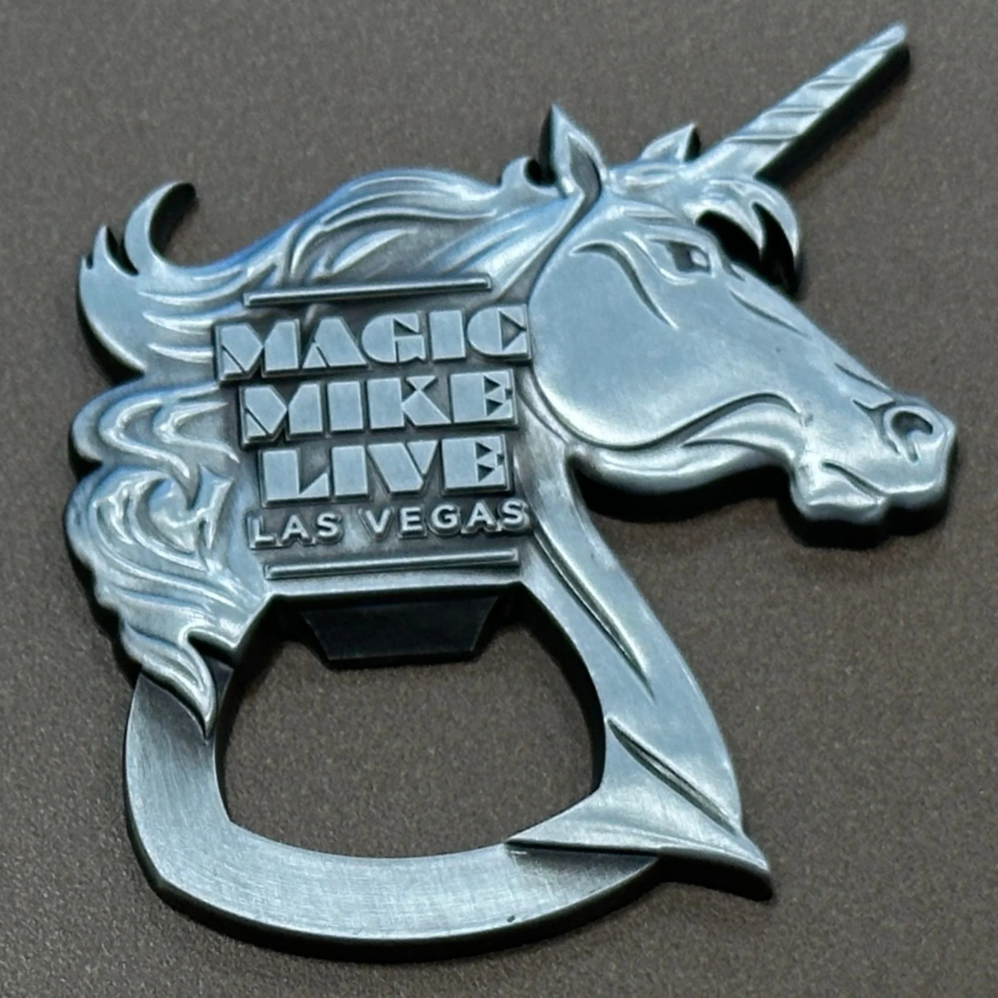 Silver metal bottle opener in the shape of a unicorn with the words "Magic Mike Live" and "Las Vegas" engraved on it.