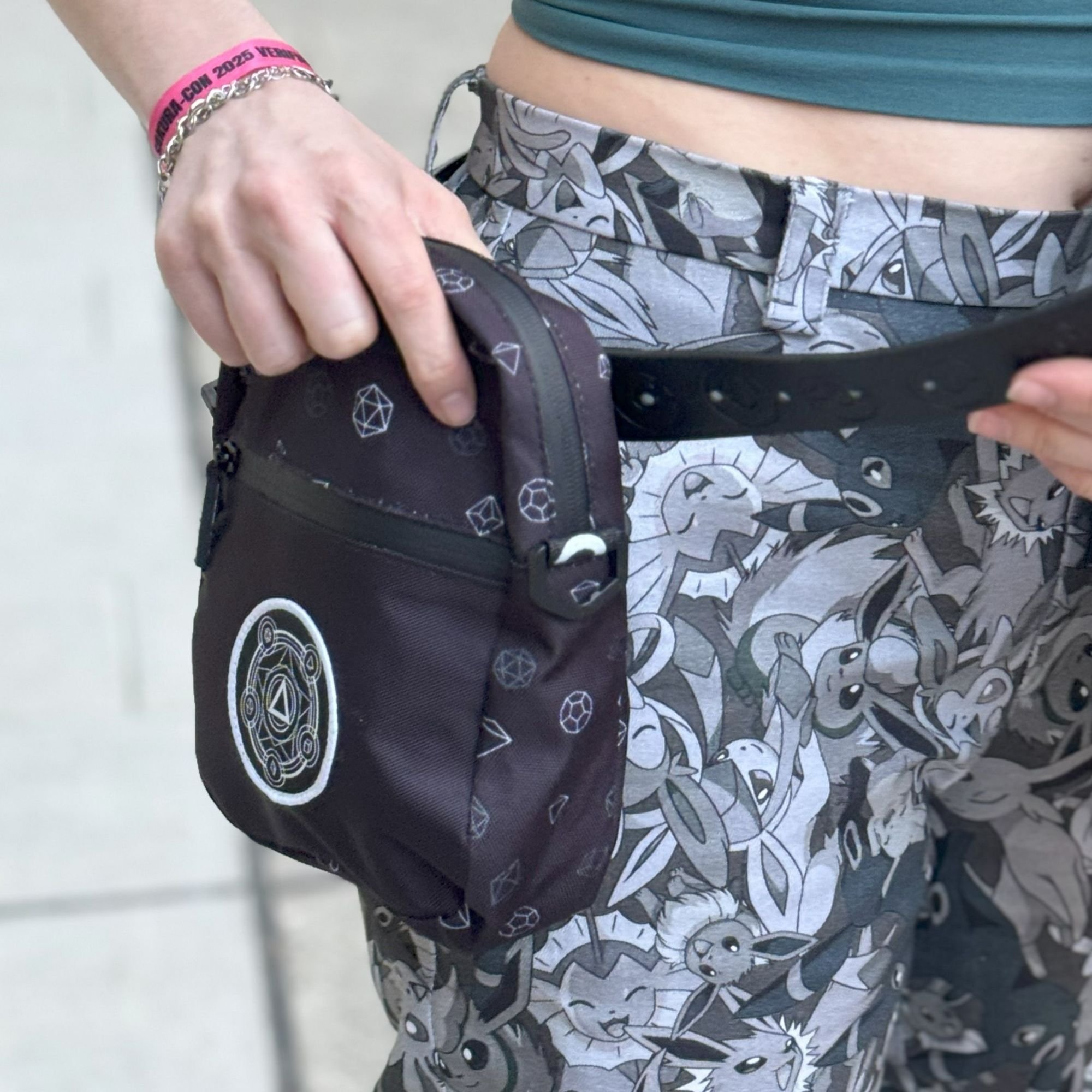 A close-up of a person holding a small black side bag with white geometric patterns.