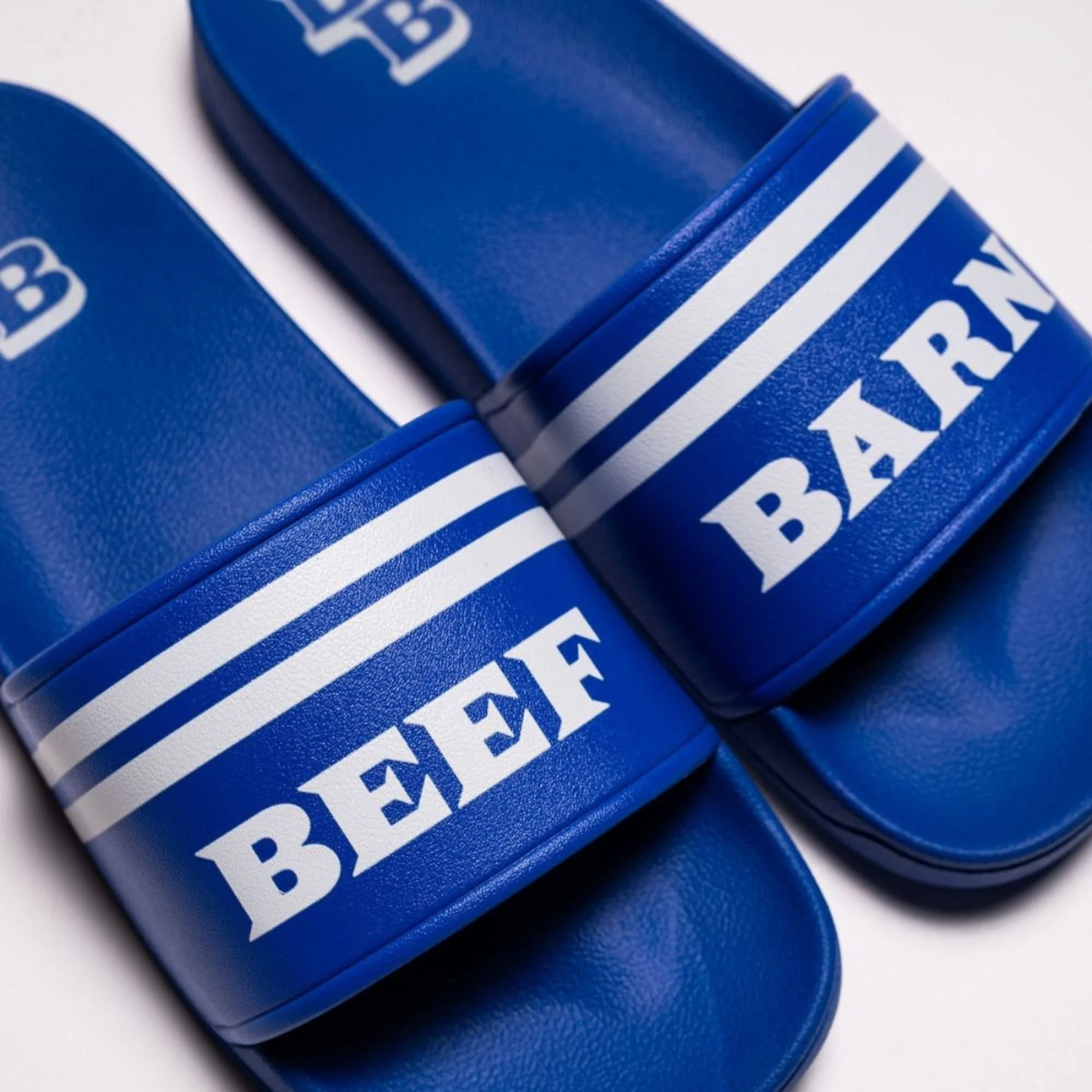 Close-up of a blue pool slide shoes with white stripes and the words "Beef Barn" in white letters.