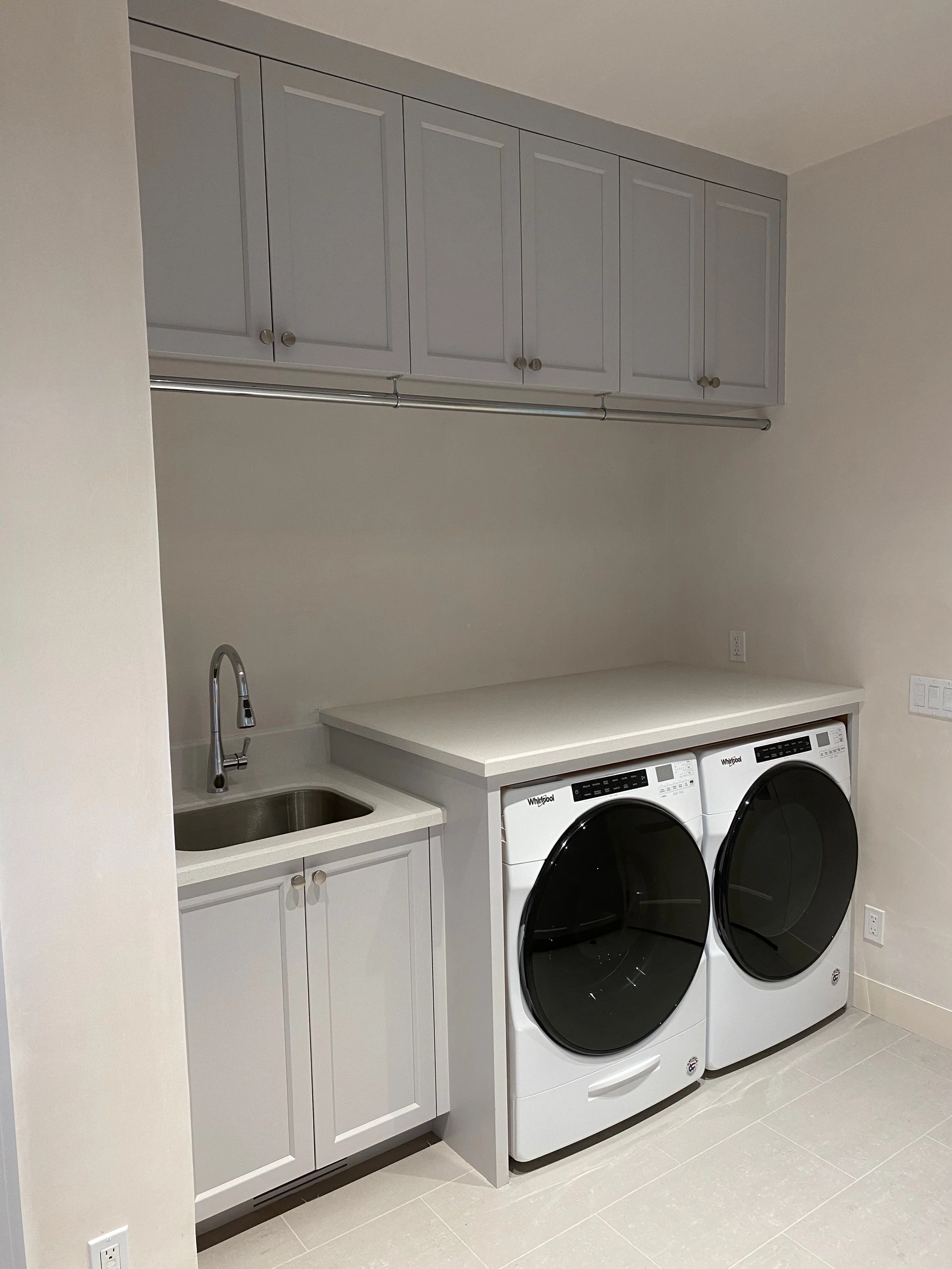 Custom laundry room cabinets above a sink and a washer-dryer combo