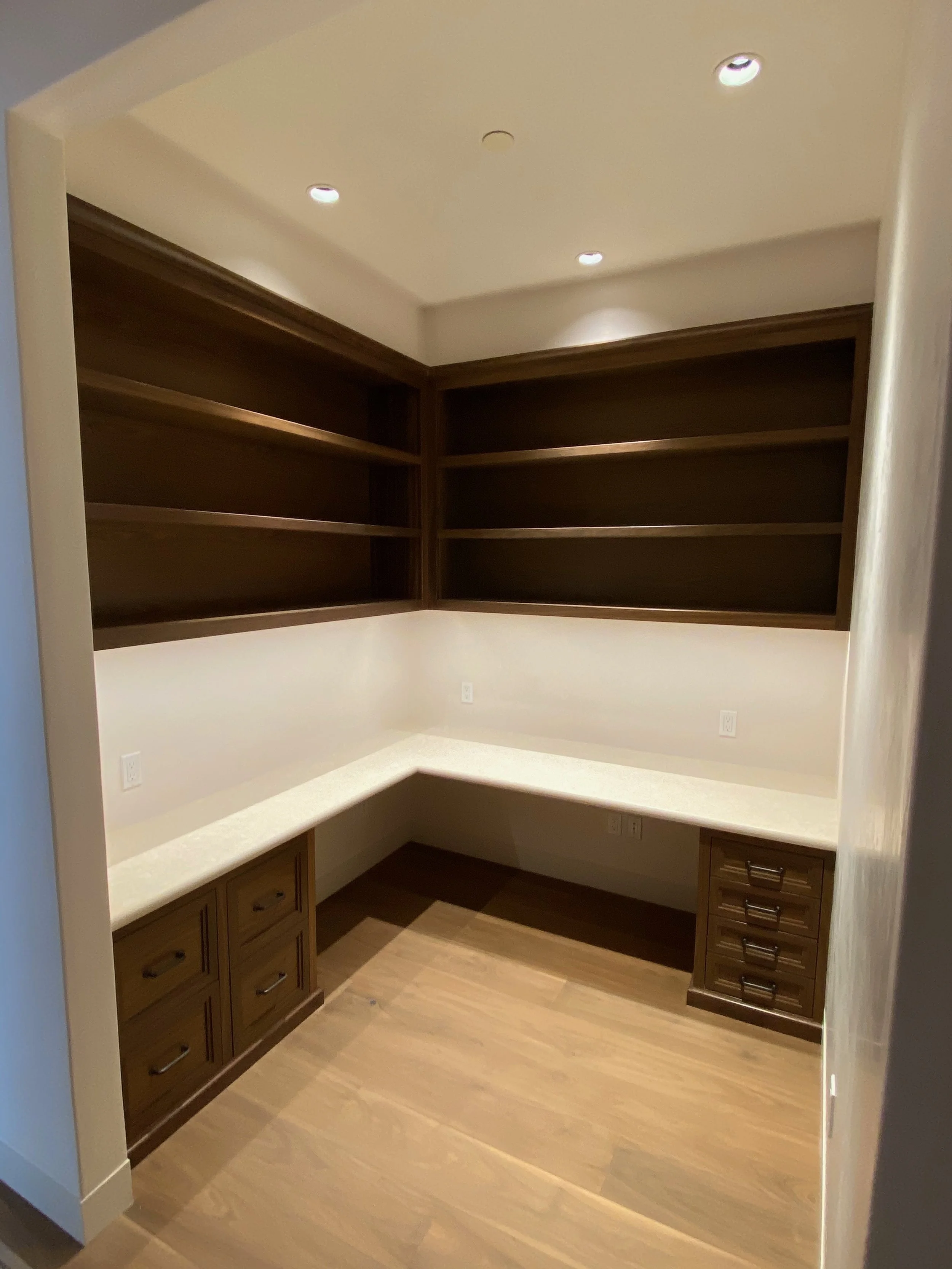 Custom walk-in closet with upper shelves, lower cabinets, and countertop in Monterey California made by custom cabinet maker Valley Mill Shop
