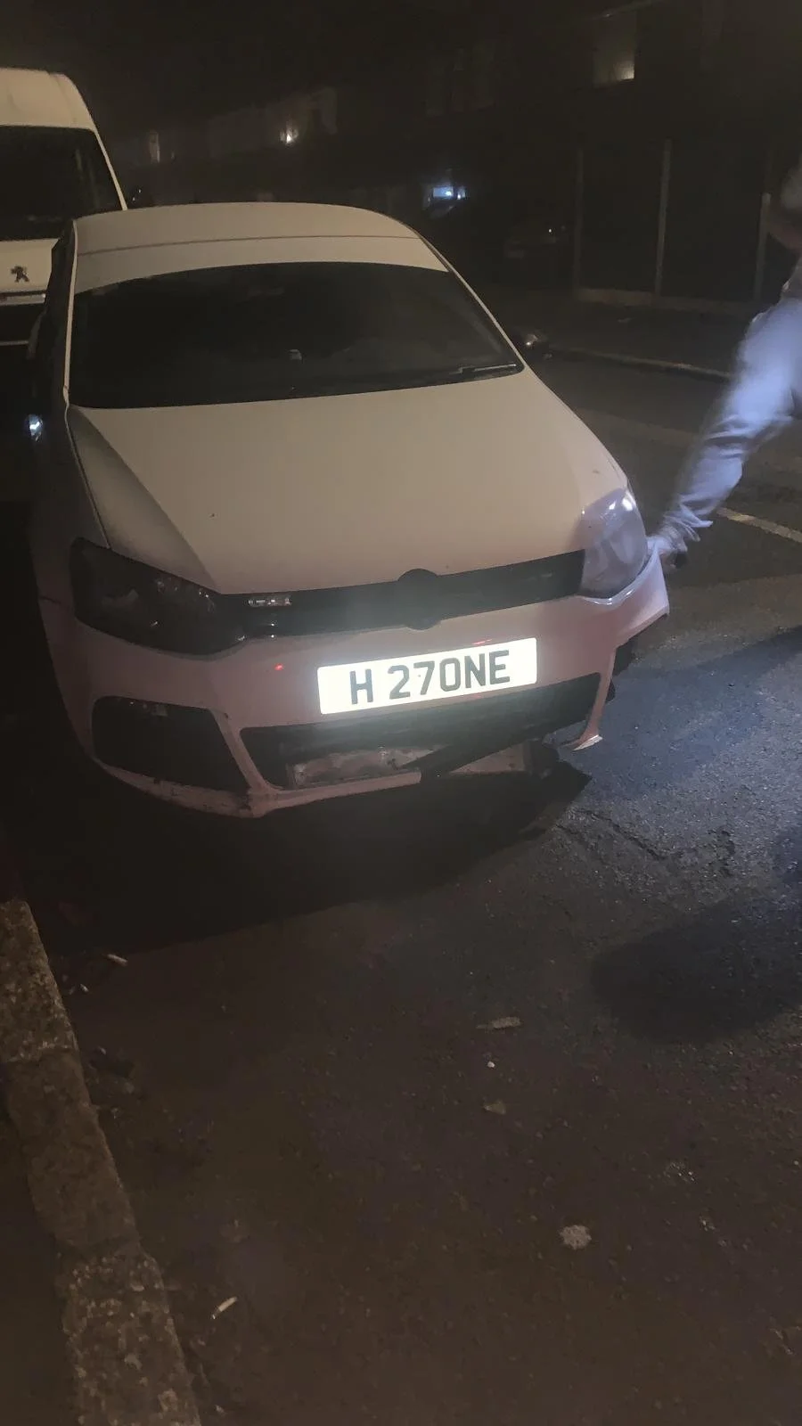 A white car with a damaged front bumper parked on a dark street at night, with a license plate that reads "H 270NE."