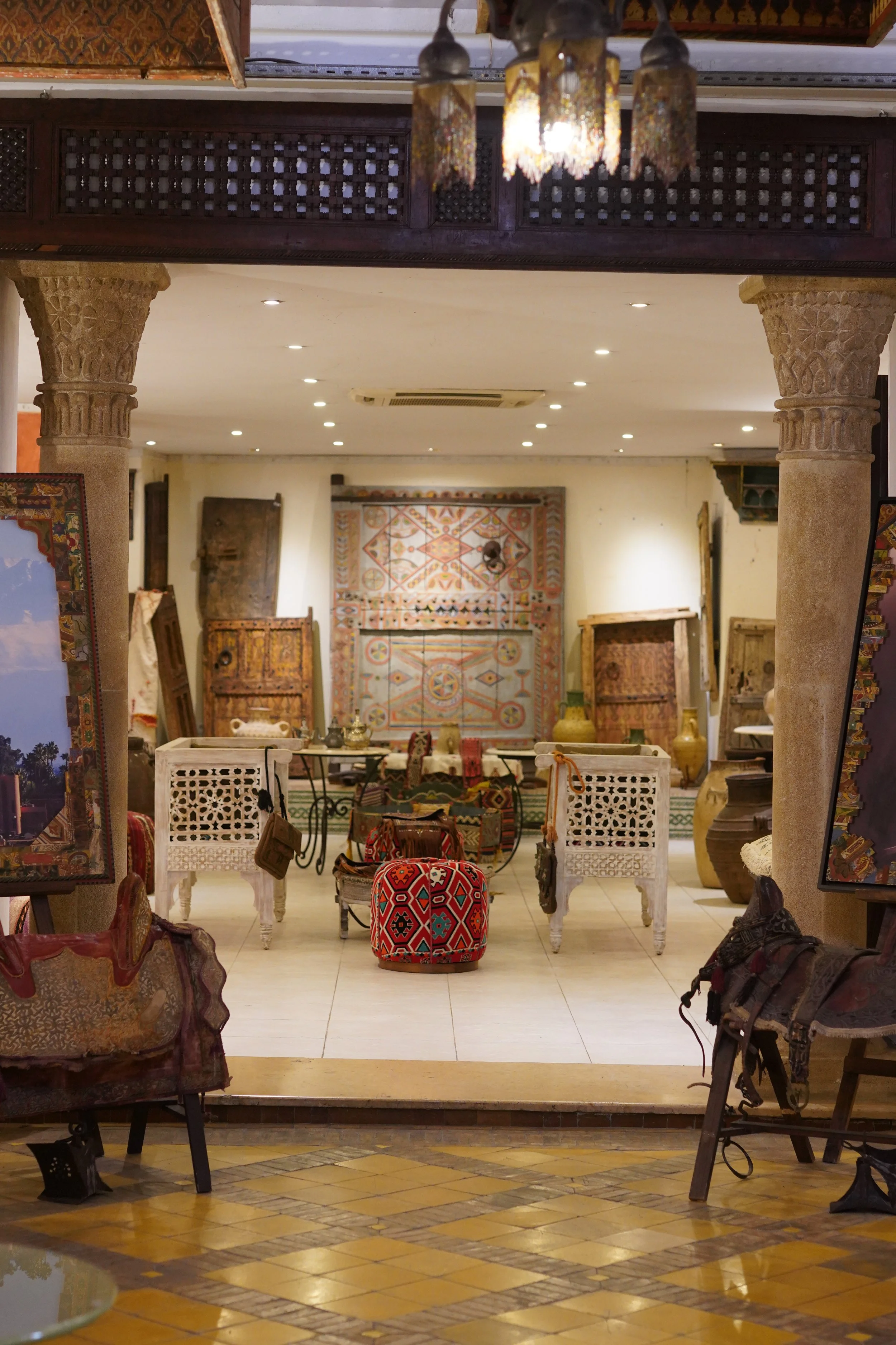 Intérieur d'un magasin d'antiquités ou d'artisanat avec de nombreux objets en bois, textiles et poteries, vue vers un arrière-plan avec des tapis et des armoires en bois, ambiance chaleureuse et décorative.