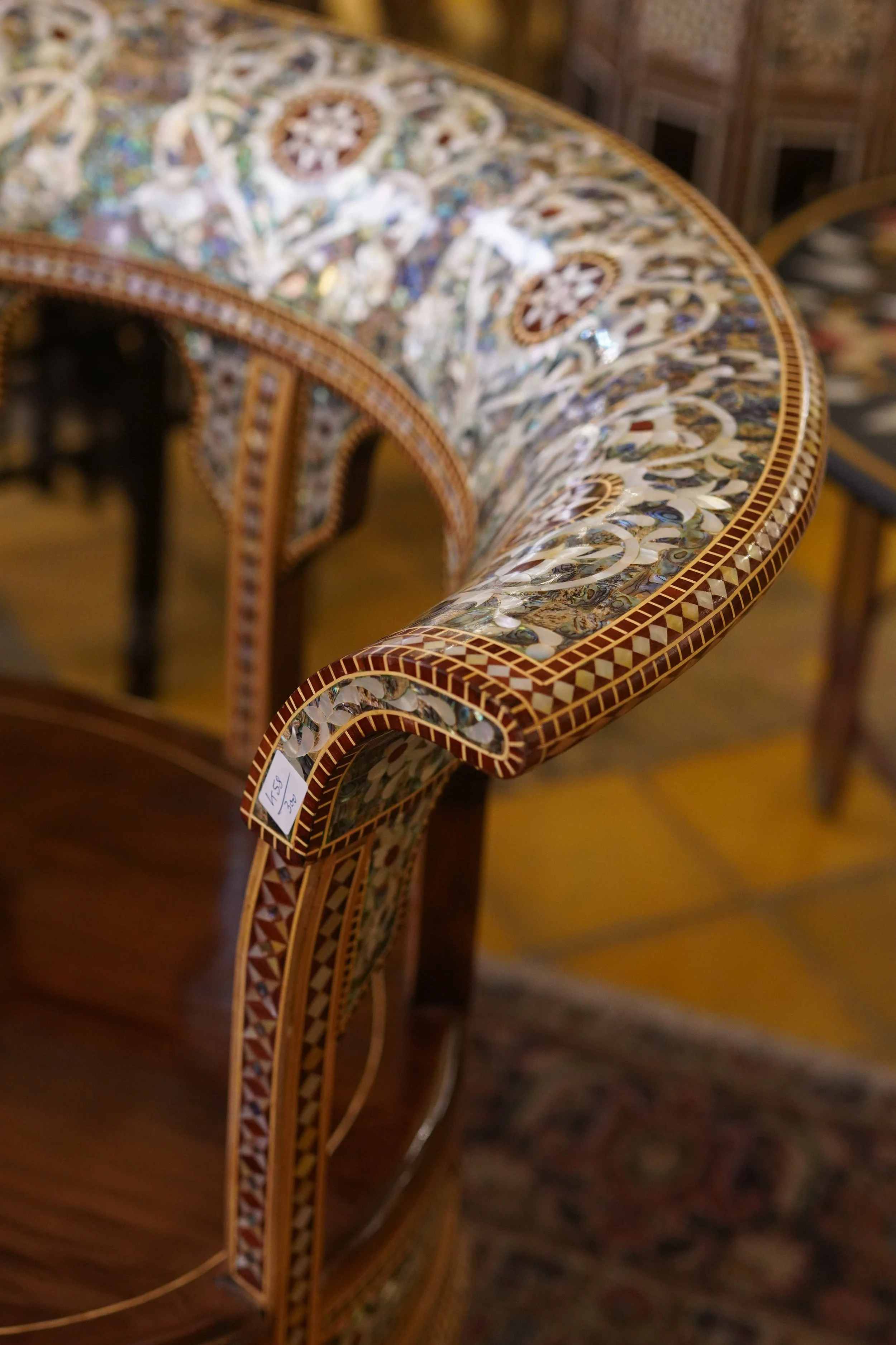 Une table en marqueterie de pierres incrustées de différentes formes et couleurs, avec un motif complexe, entourée d'autres meubles en bois décorés, dans une pièce élégante.