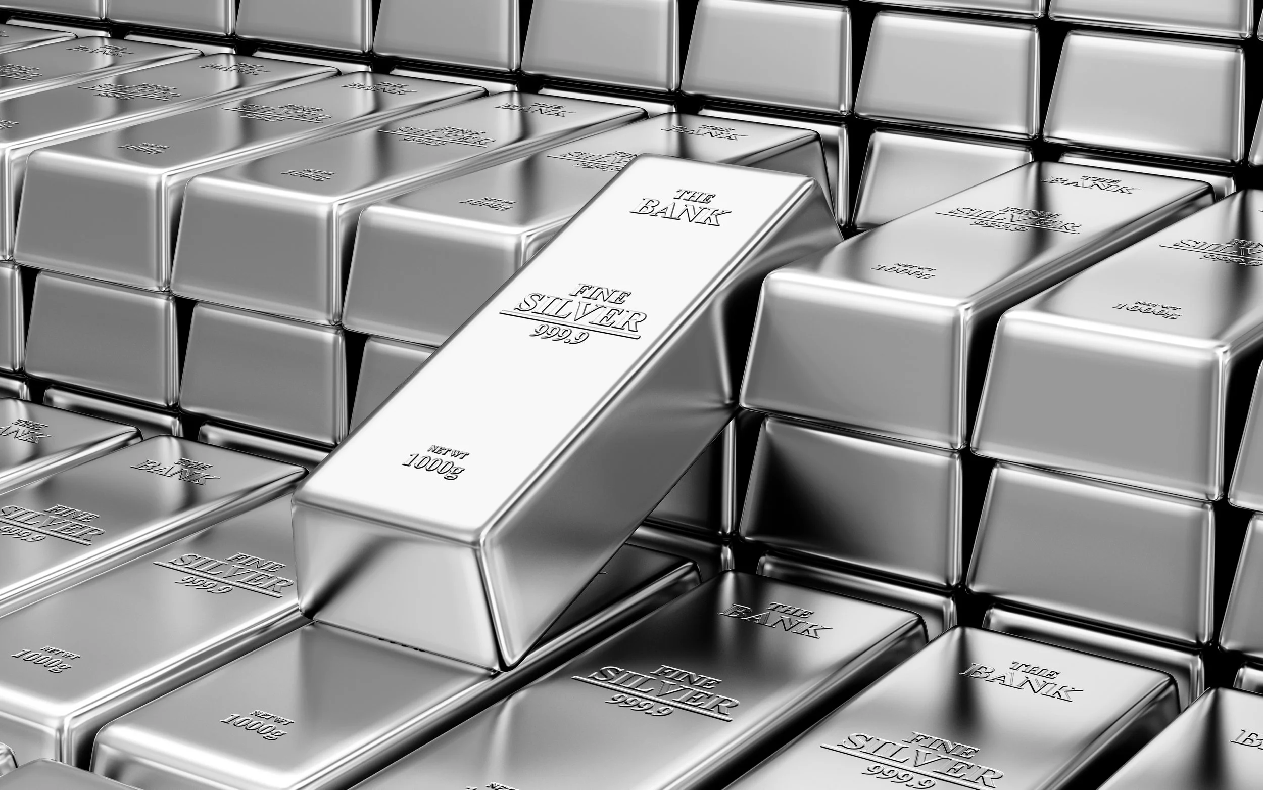 Multiple silver bars of pure silver stacked together, with the words 'The Bank', 'Fine Silver', '.9999', and '1000g' inscribed on each bar.