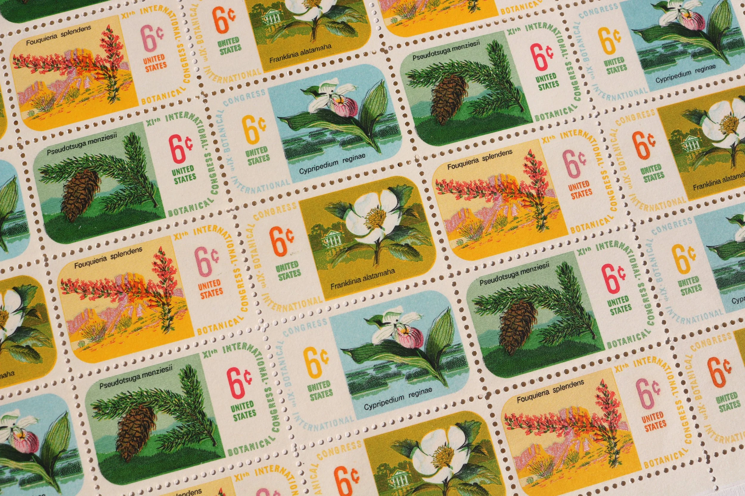 A sheet of vintage postage stamps featuring various illustrations of plants, including magnolias, pines, and other flowering and leafy plants. Each stamp has a different plant illustration, with some labeled with their scientific names. The stamps are colorful, with backgrounds in shades of yellow, blue, green, and beige, and include printed denomination values of 6 cents in red and other text.