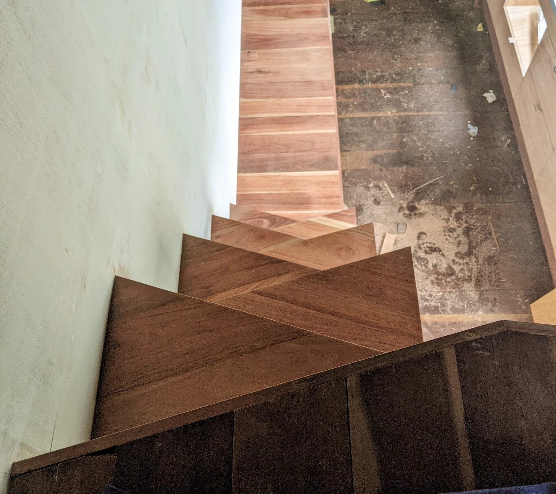 Unfinished interior space showing wooden paneling and exposed wall and floor with construction debris.