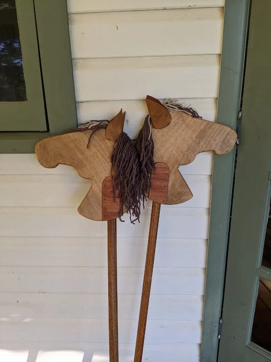 Wooden butterfly-shaped yard decoration with yarn hair hanging on a wall.