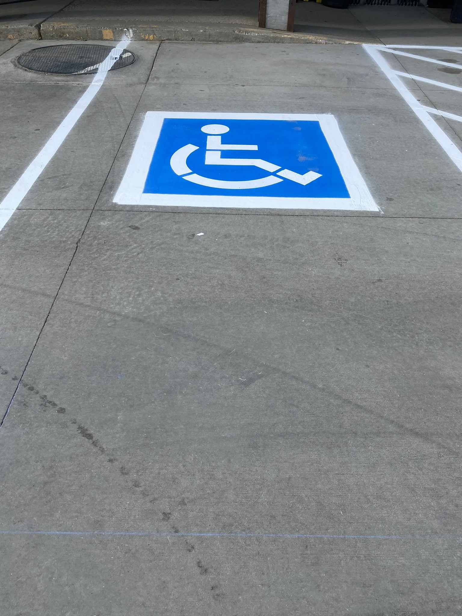 A parking space marked for handicapped parking with a blue and white wheelchair symbol painted on the concrete ground.