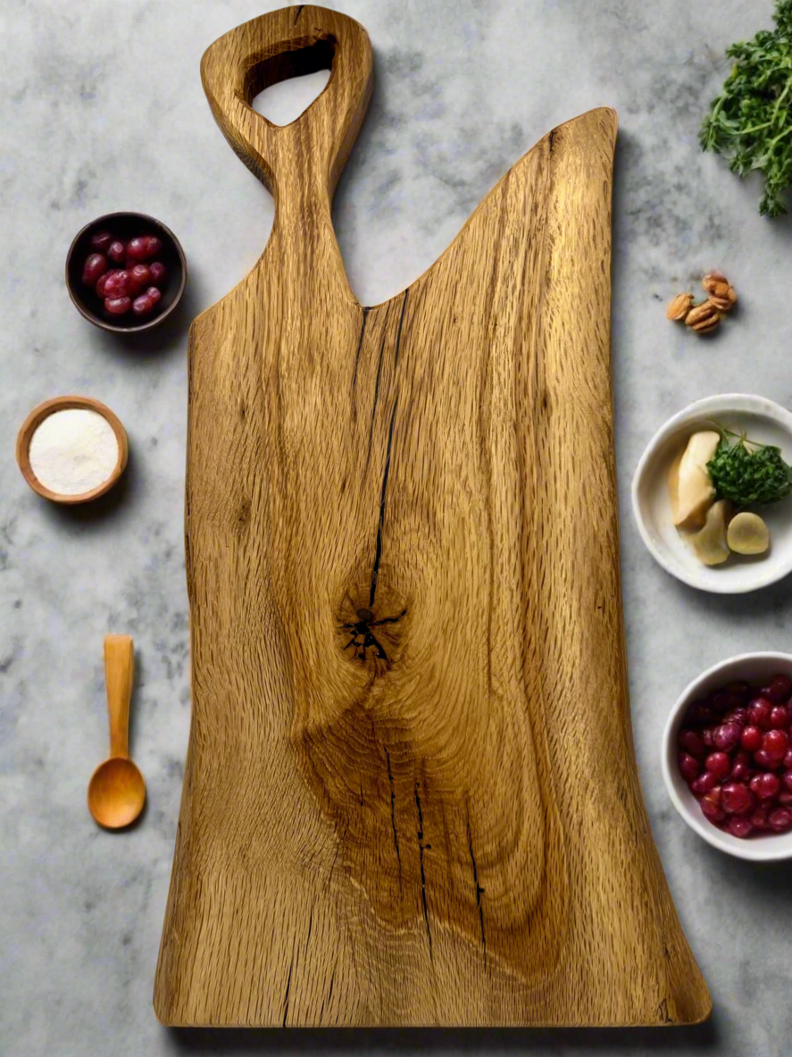 A large wooden cutting board with a handle, surrounded by small bowls of cranberries, salt, walnuts, cheese, herbs, and garlic on a marble countertop.