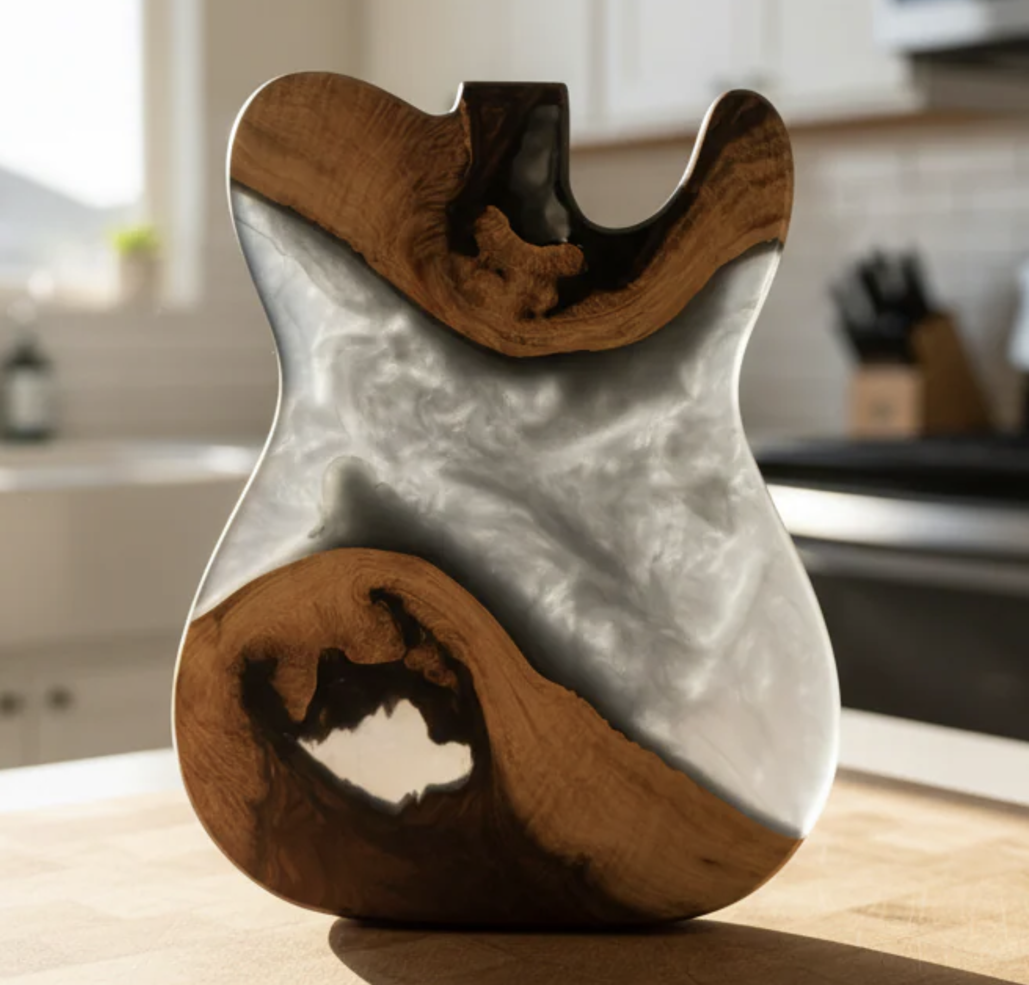 A wooden sculpture with a smooth, polished surface and dark carved details, resting on a white pedestal in a room with blurred background.