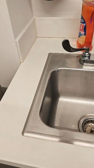 Fuente de cocina de acero inoxidable con detergente líquido y un grifo.
