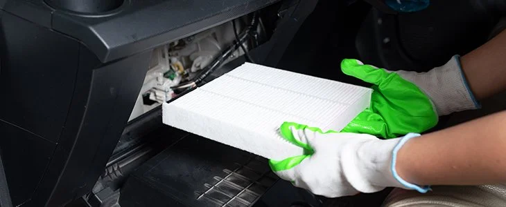 Person wearing white gloves holding a stack of white papers or sheets near a printing or scanning machine.
