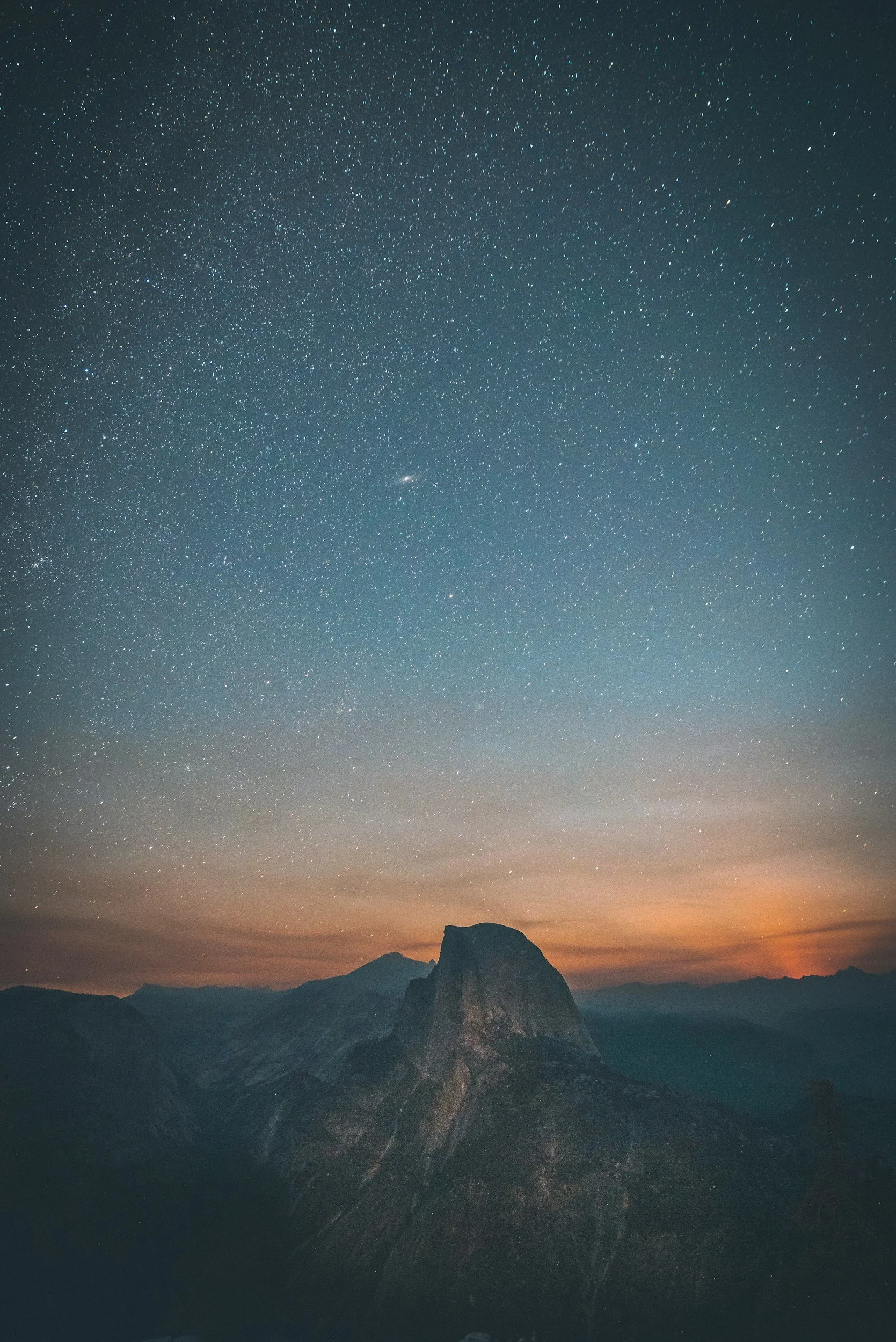 Night sky filled with stars over a mountain landscape at sunset.