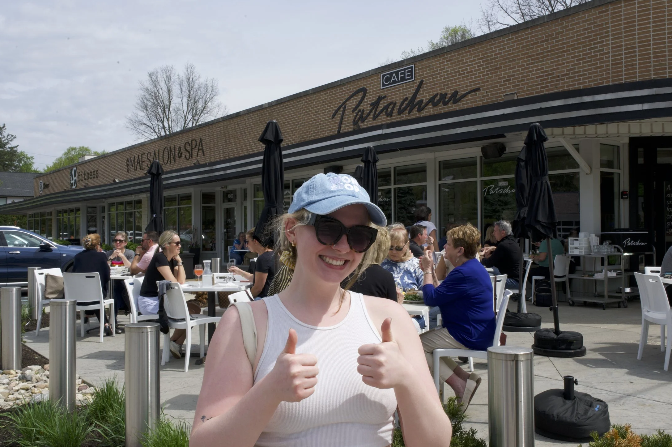 Jackie standing outside of the flagship Cafe Patachou location, giving two thumbs up.