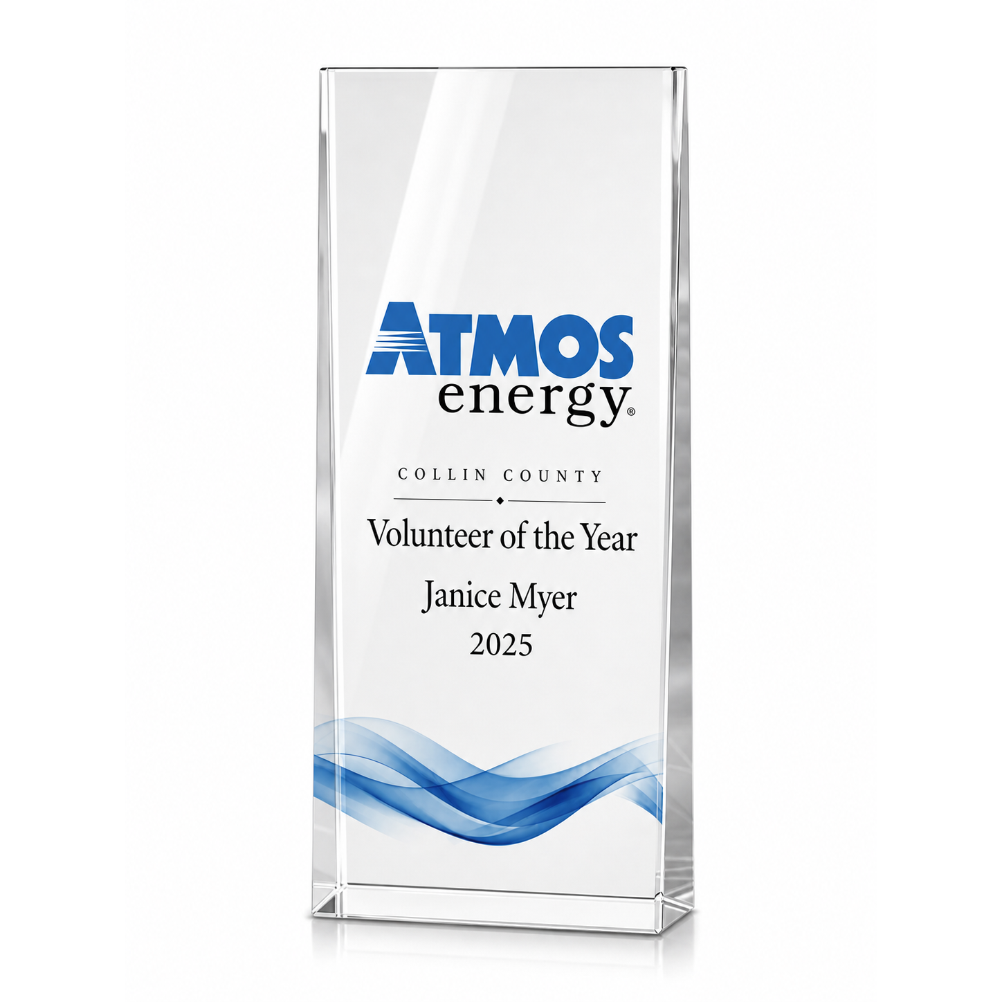 A glass award plaque with blue wave design at the bottom, displaying the logo and name "ATMO energy", and inscribed with "Collin County Volunteer of the Year Janice Myer 2025."