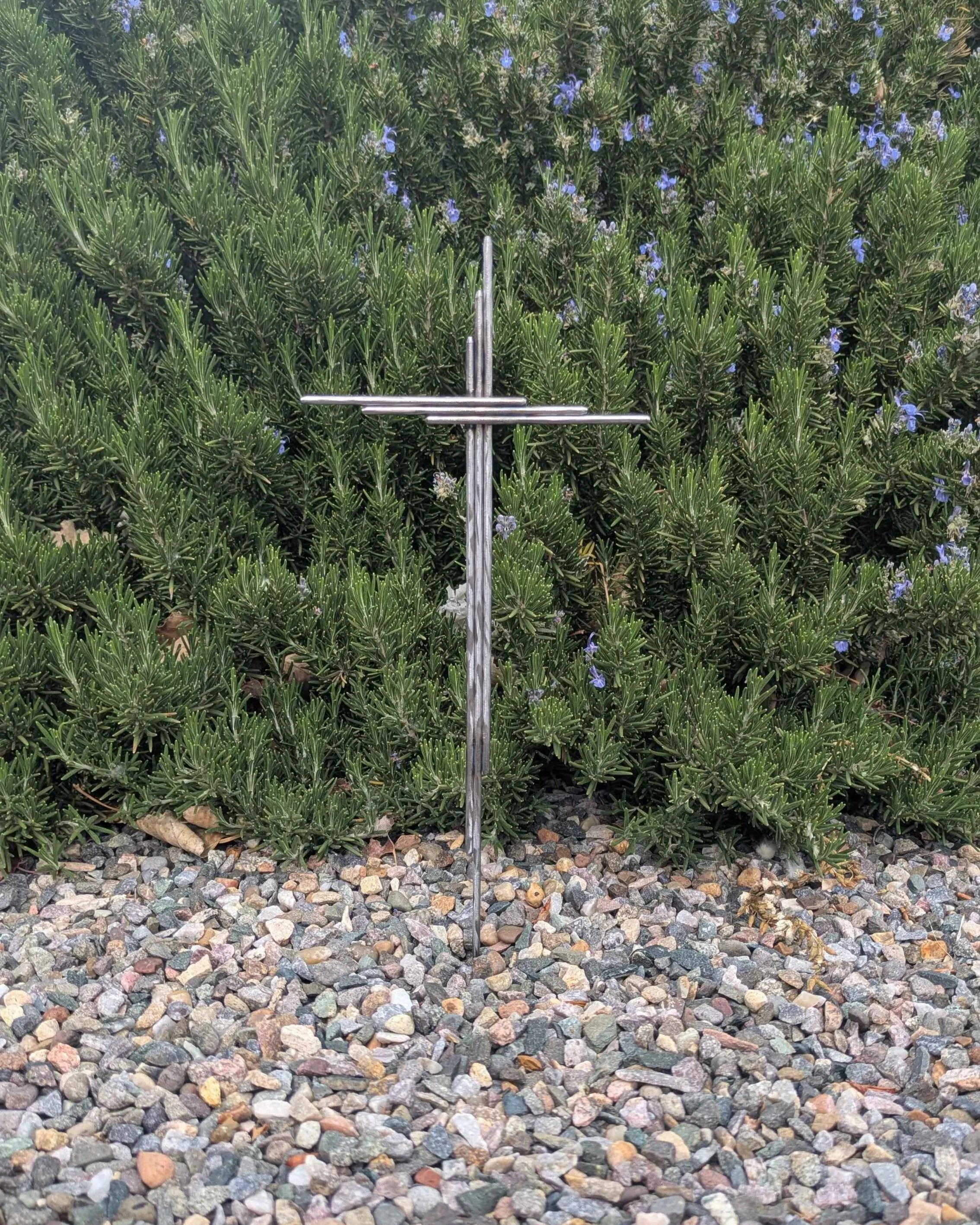 A metal art yard cross made from polished steel rods.