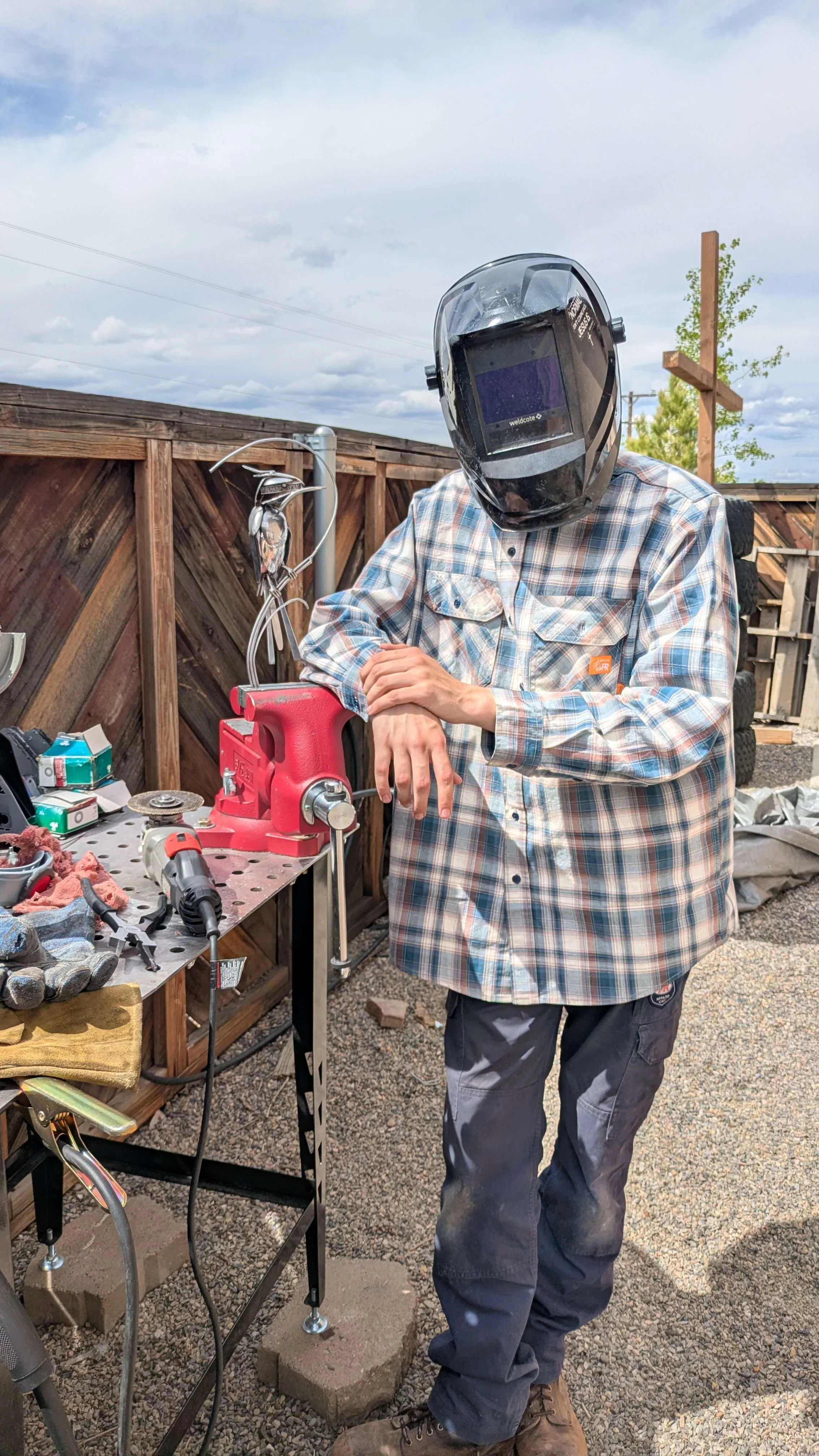 A welder standing next to a metal art bird sculpture.