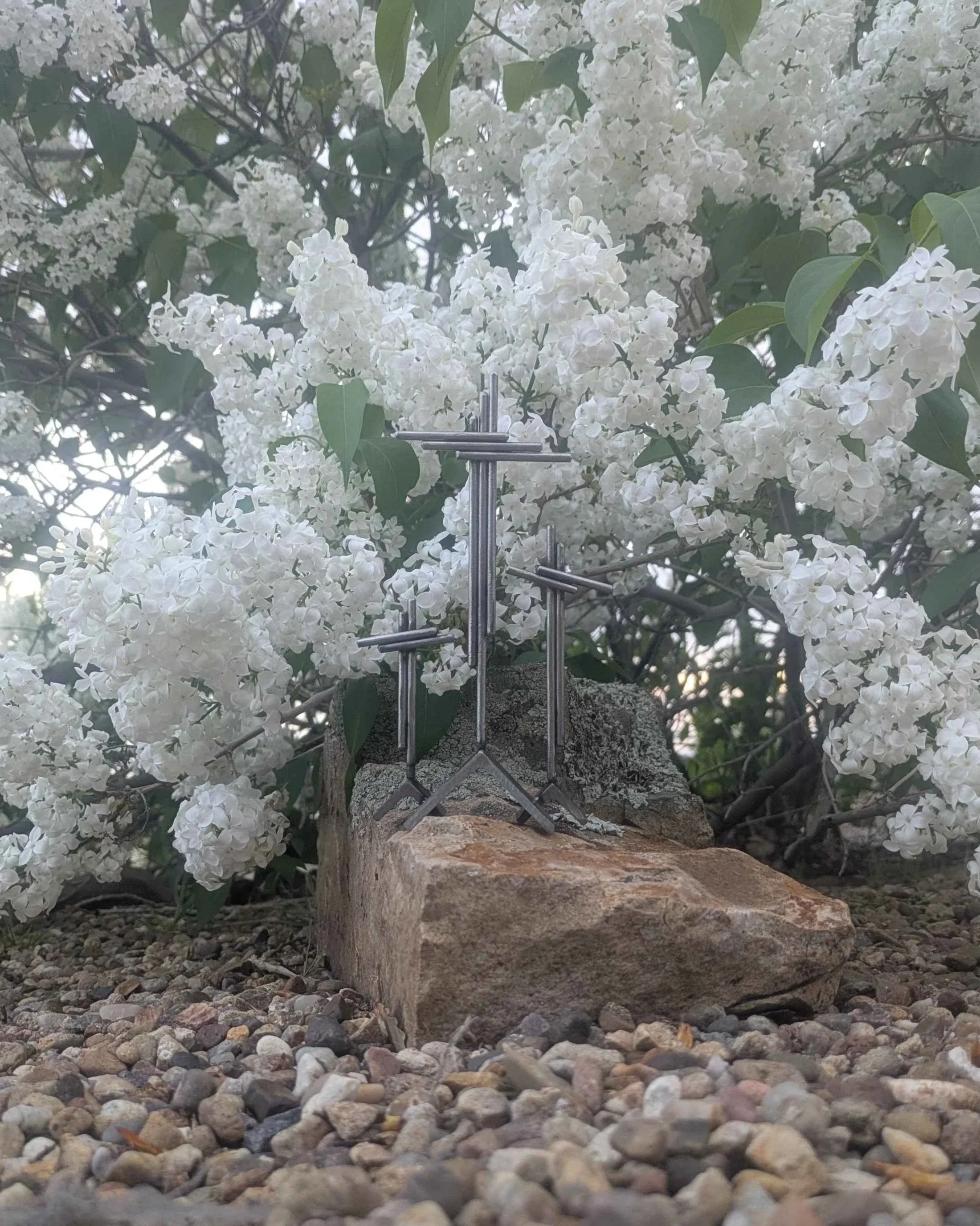 A metal art display of three crosses on three hills, made from rods and angle iron.