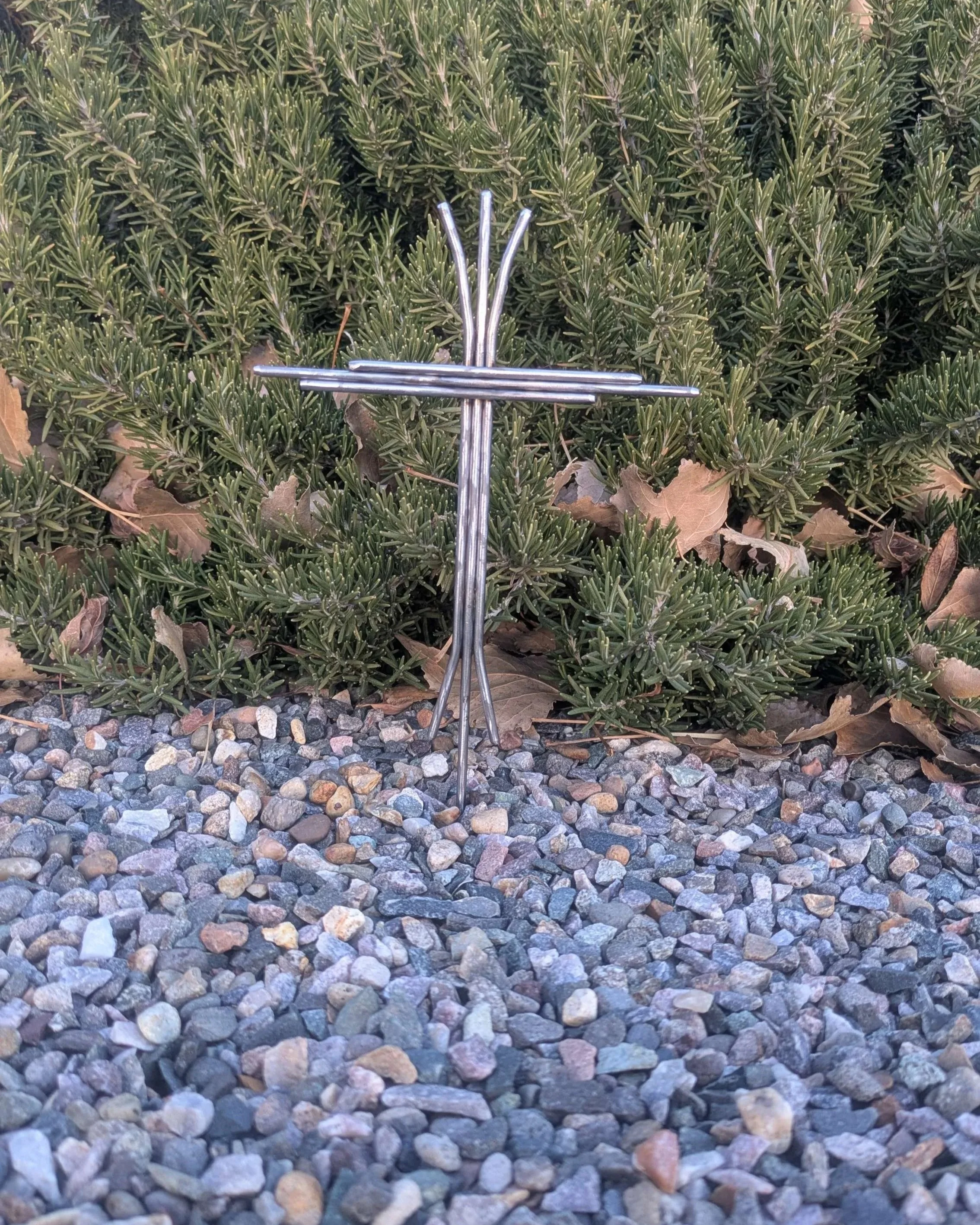 A metal art cross welded together with pieces of carefully bent metal rods.