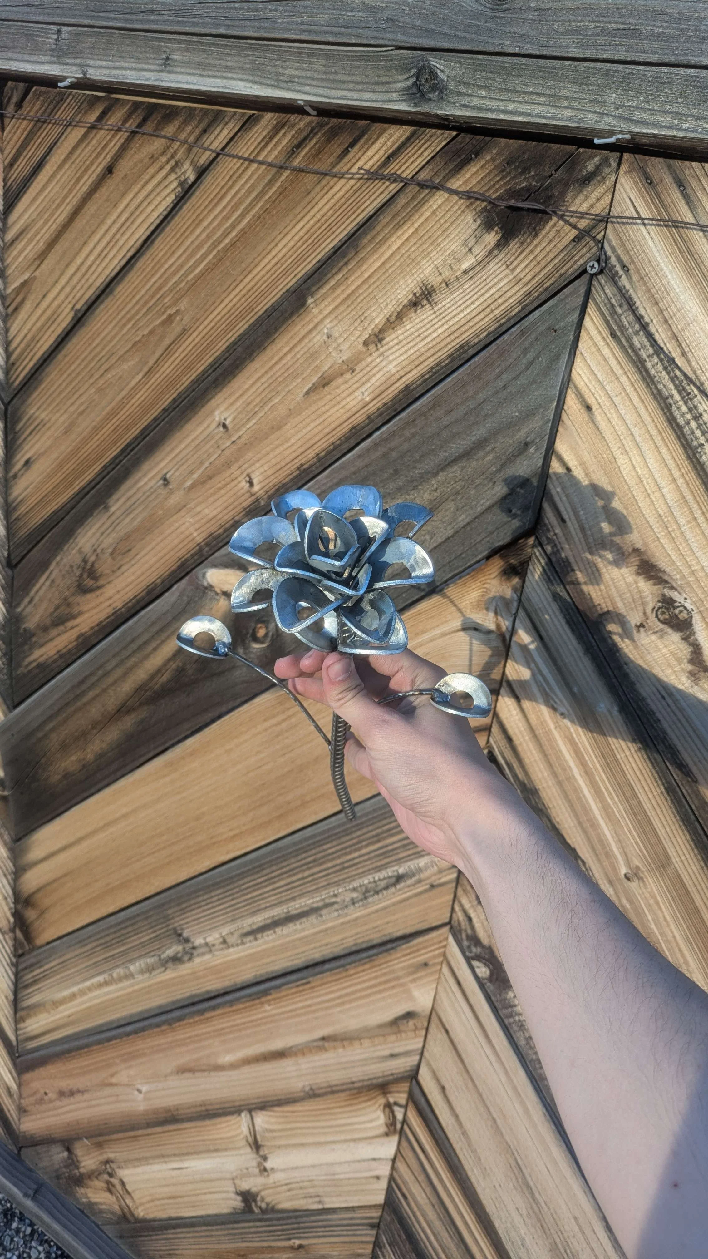 A large metal art flower made from industrial parts, laying on its side as a piece of home decor.
