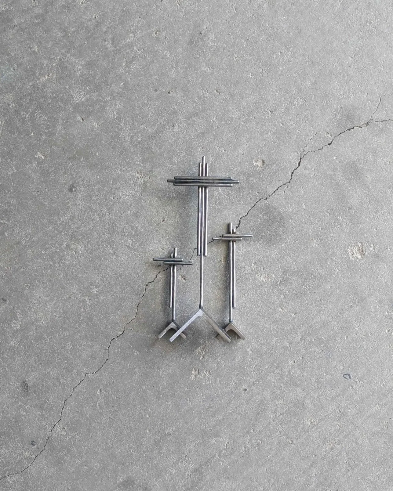 A metal art display of three crosses on three hills, made from rods and angle iron.