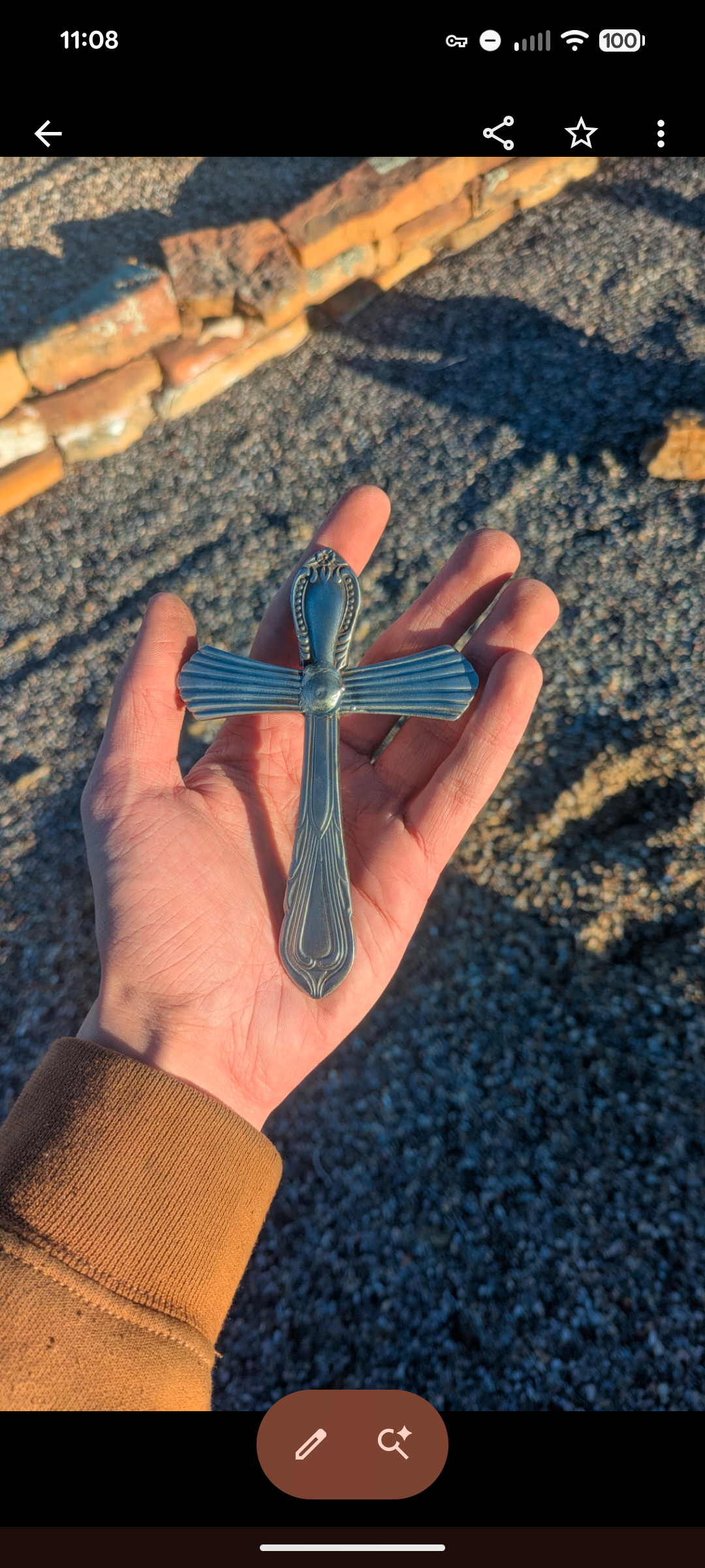 A hand holding a silverware cross.