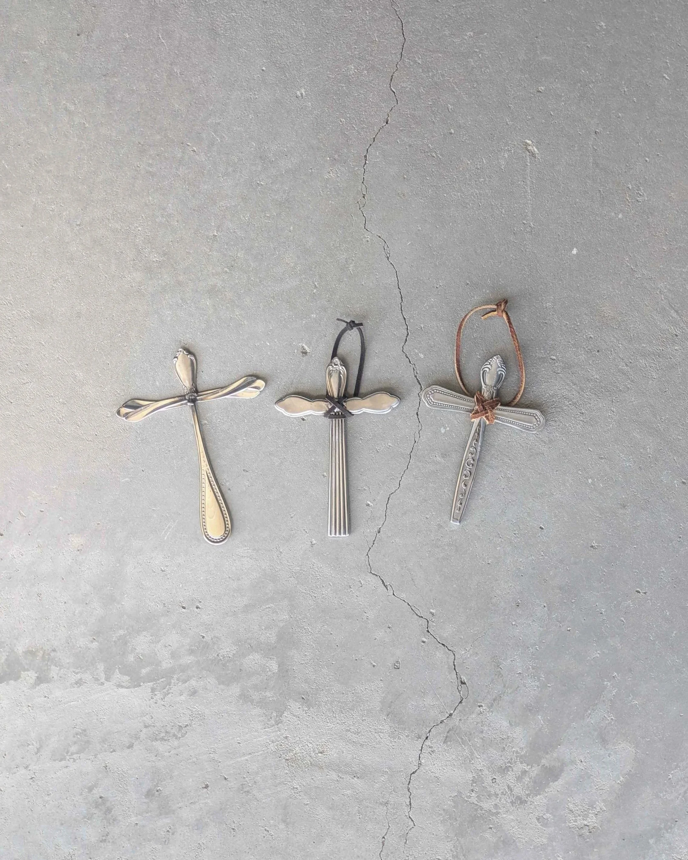 Three handmade crosses made from welded together silverware, two of which with leather hanging straps